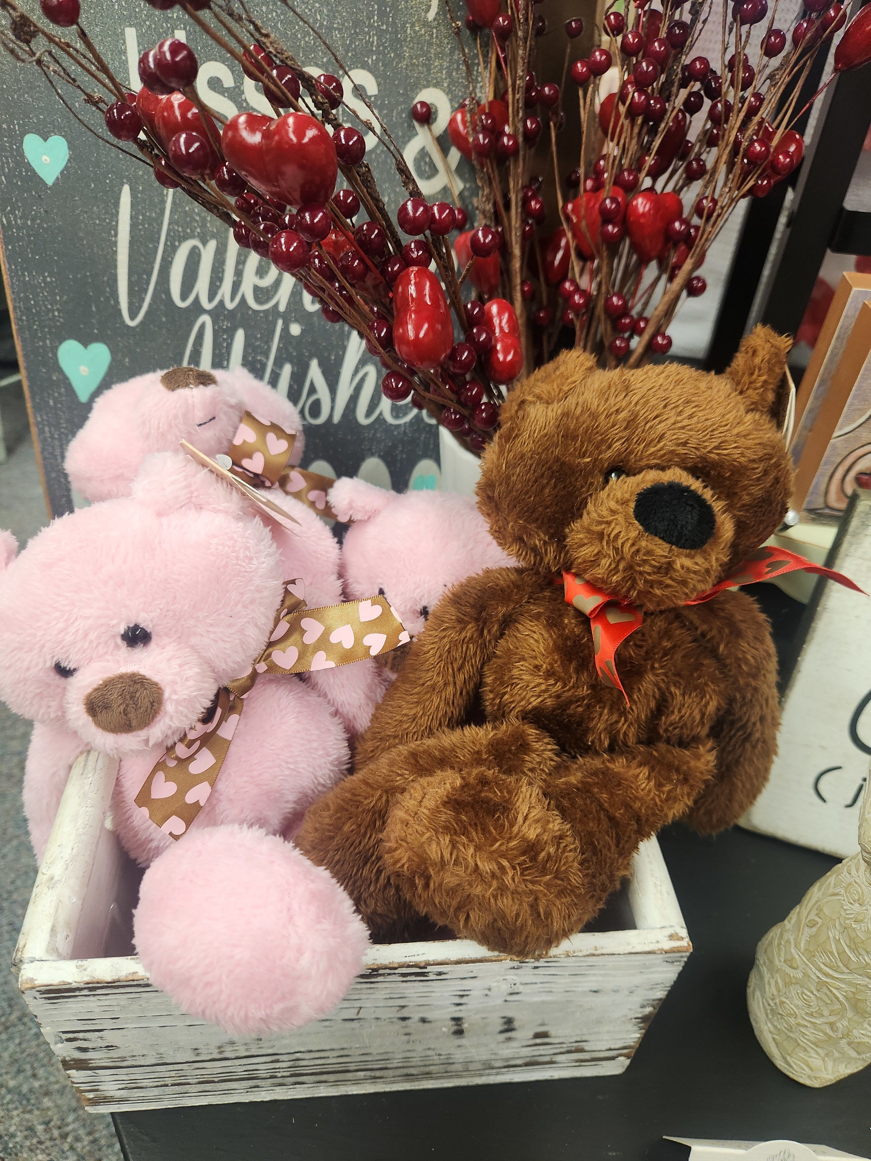 Plush teddy bears in a wooden crate with red berry stems