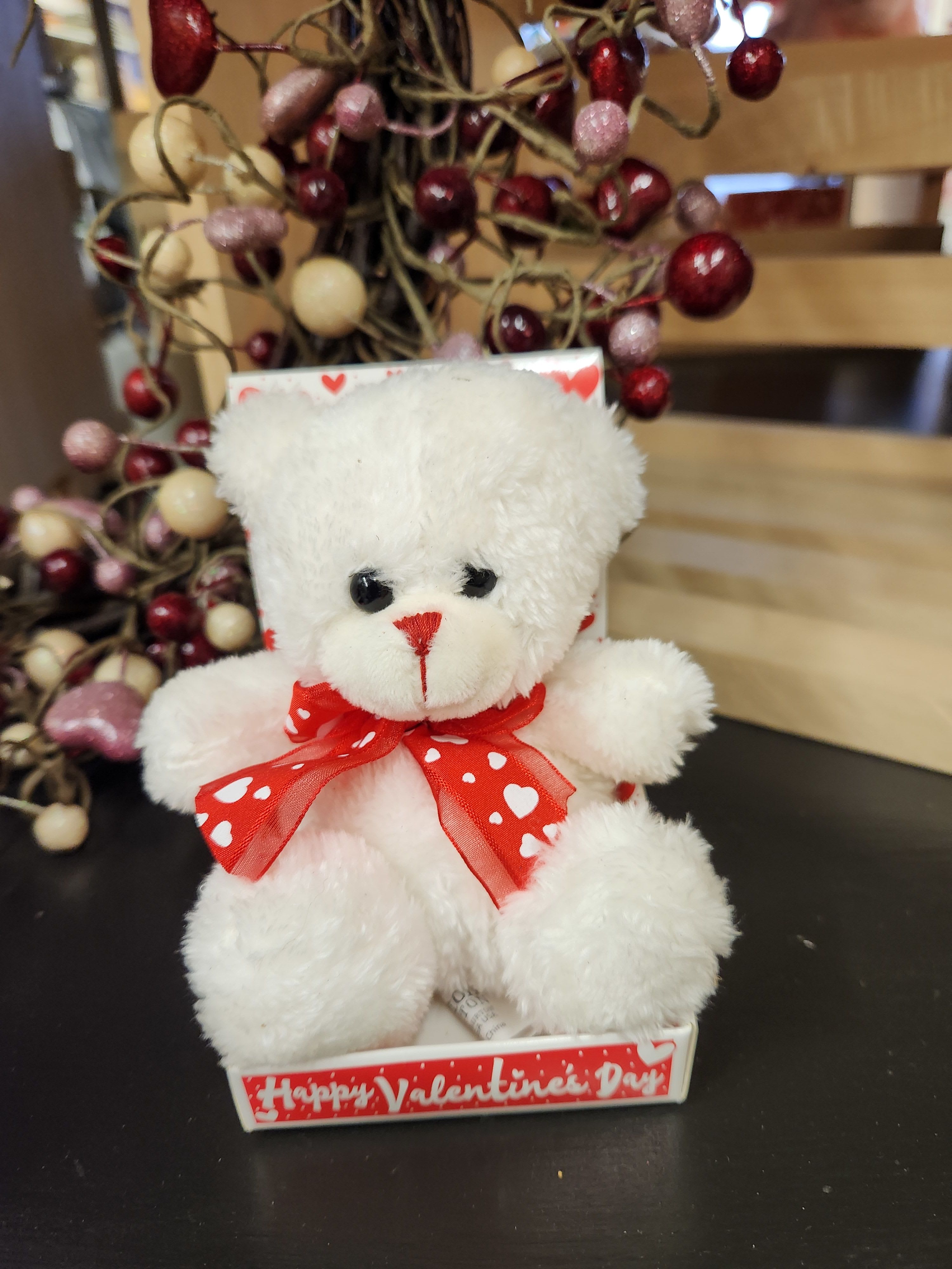 White teddy bear with a red heart ribbon in a Valentine display