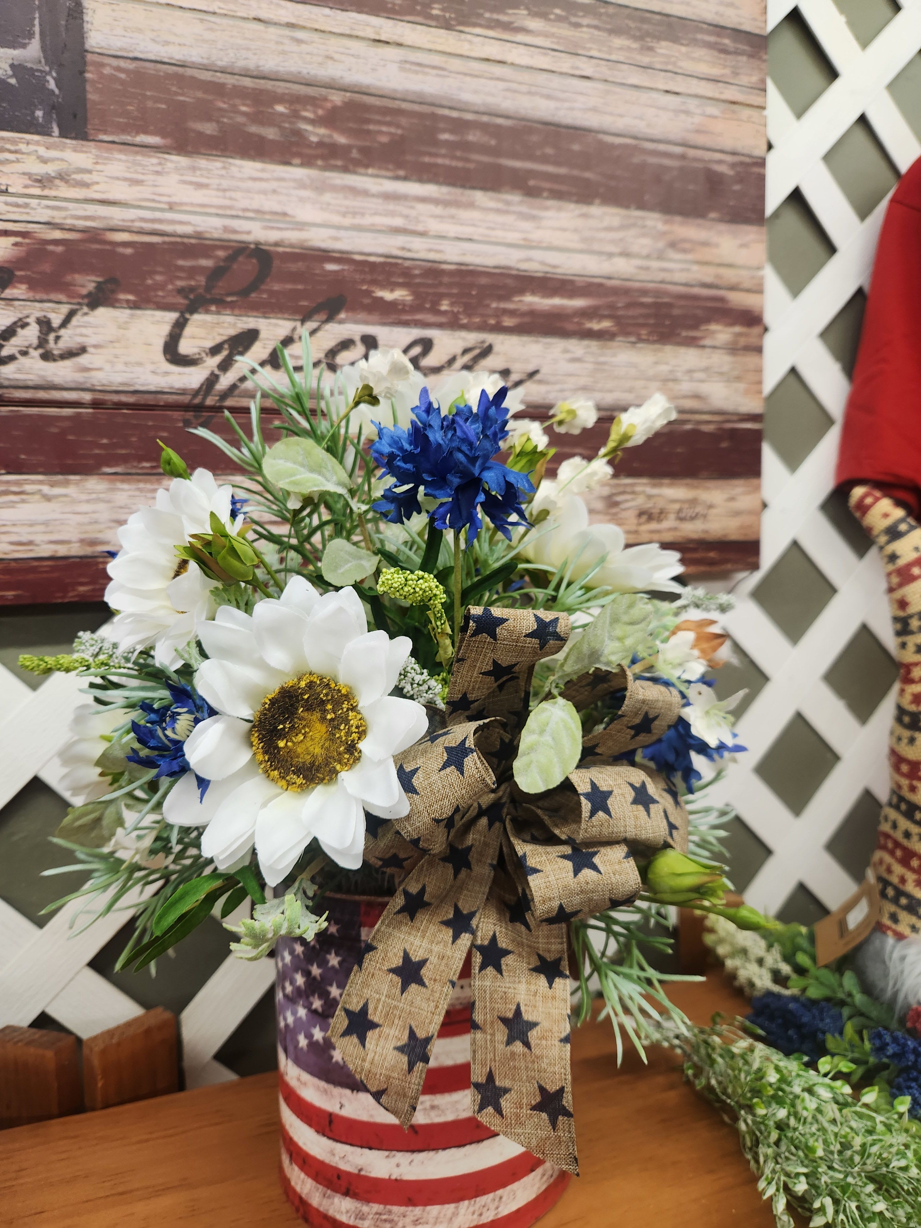 Bouquet of white and blue flowers in a patriotic tin container with a star ribbon