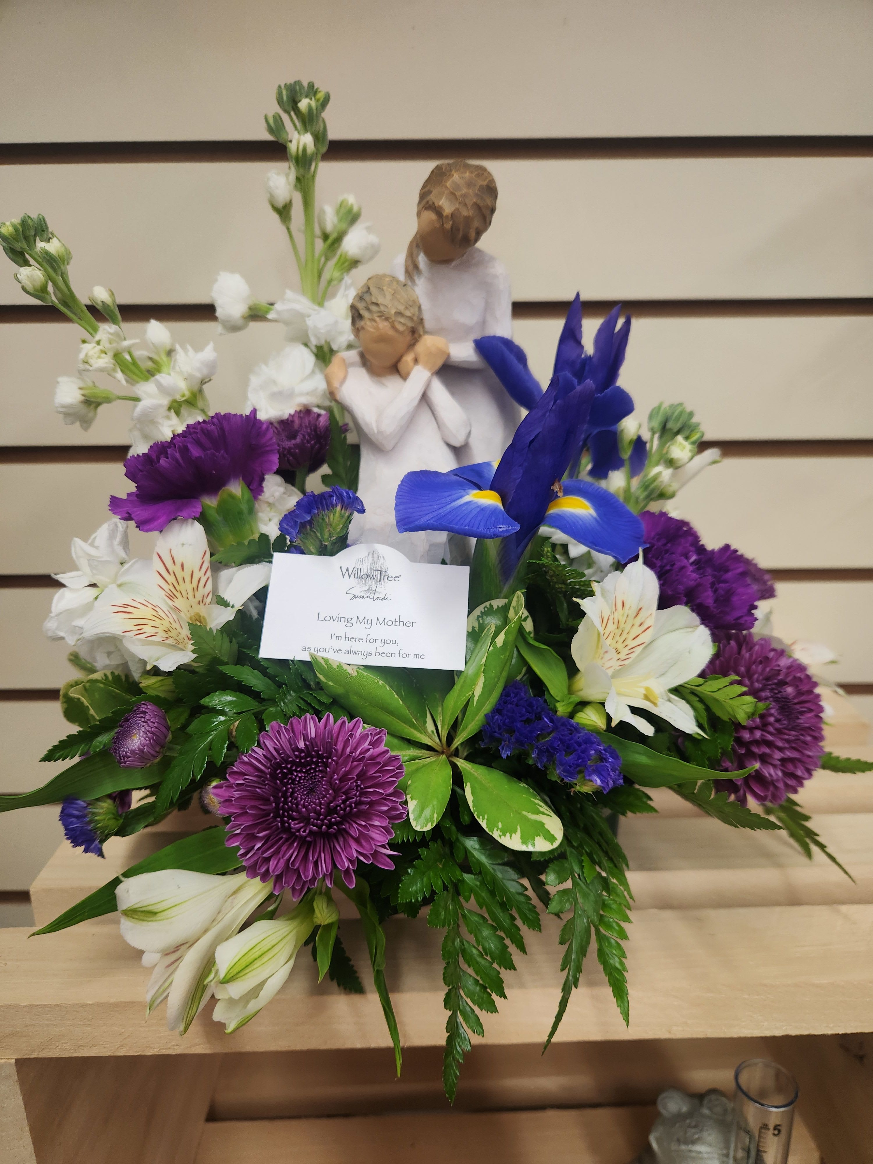 Purple and white floral arrangement with a mother-and-child figurine