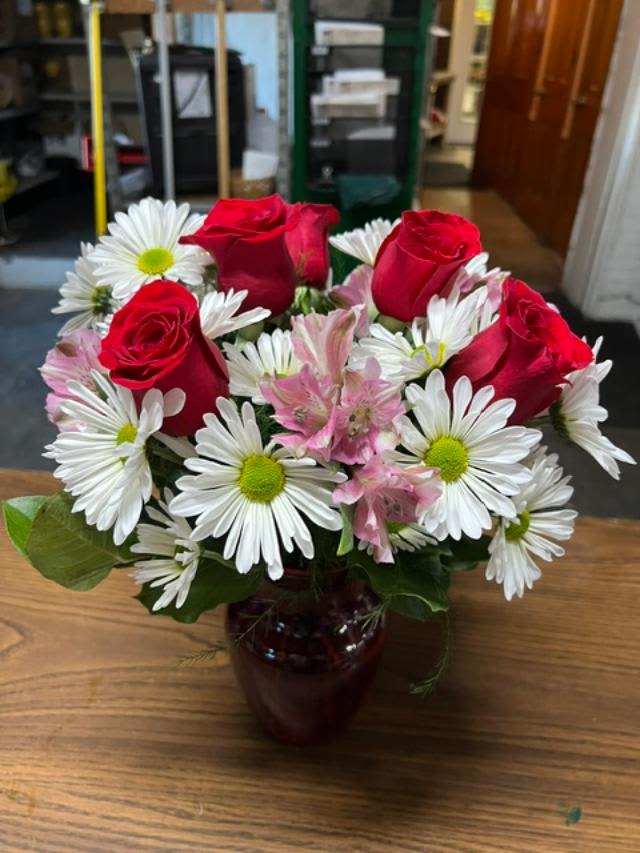 Red roses and white daisies in a dark glass vase