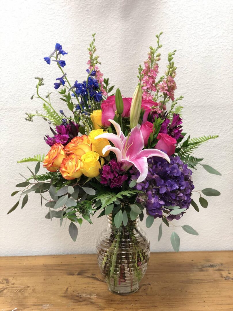 Colorful mixed bouquet in a clear glass vase with roses and lilies