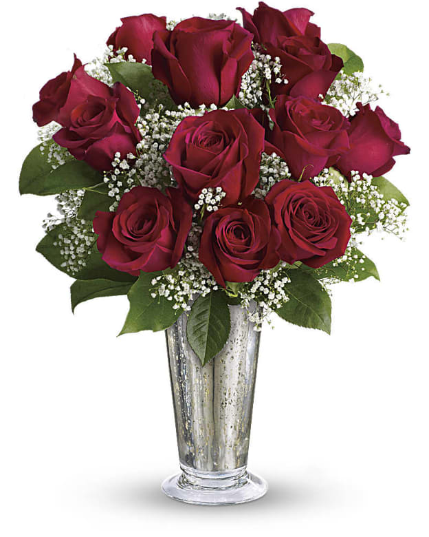 Red roses arranged in a clear glass vase with baby's breath