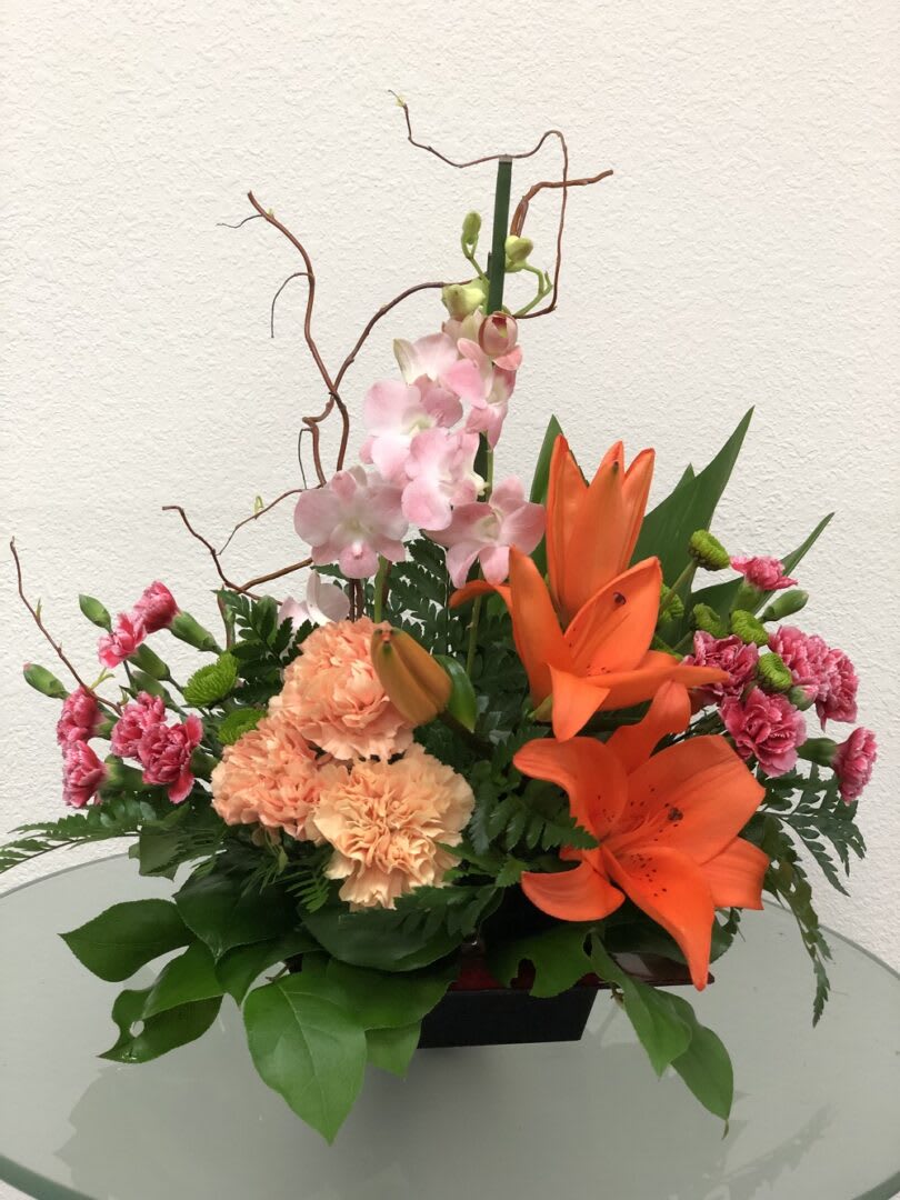 Orange lilies and pink carnations arranged in a low vase