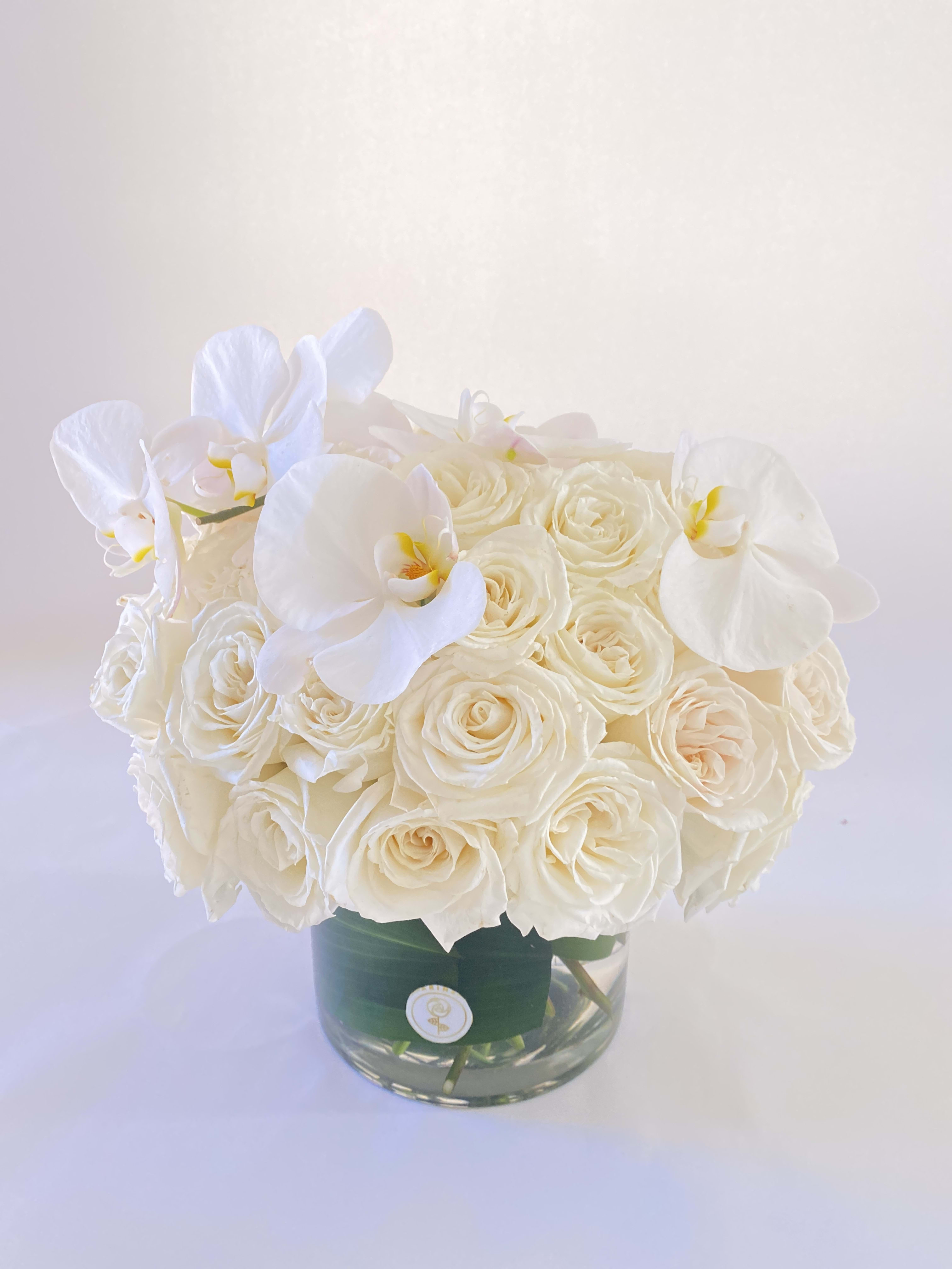 White rose bouquet with white orchids in a glass vase