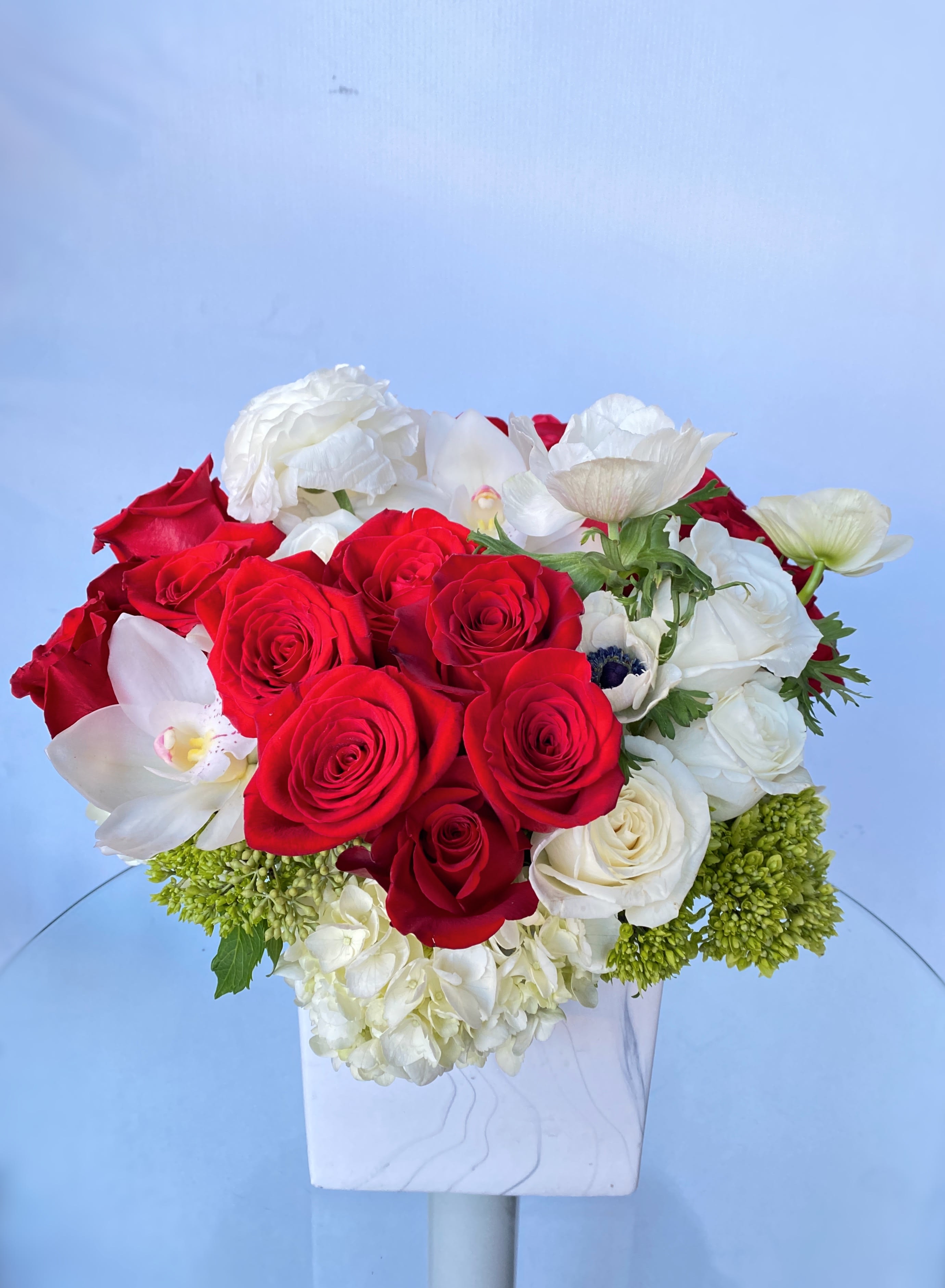 Red and white rose arrangement in a white vase