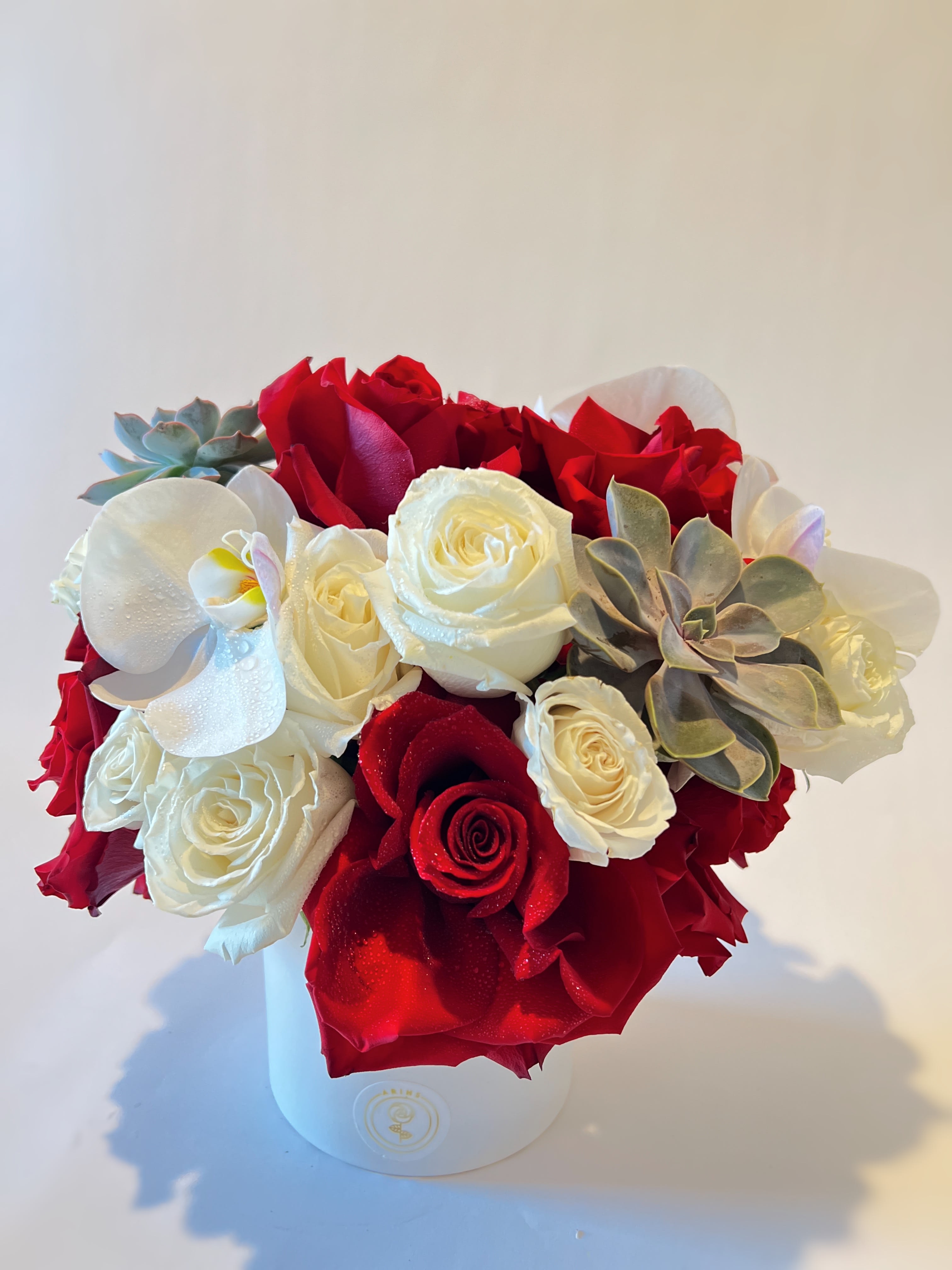 Bouquet of red and white roses with succulents in a white box