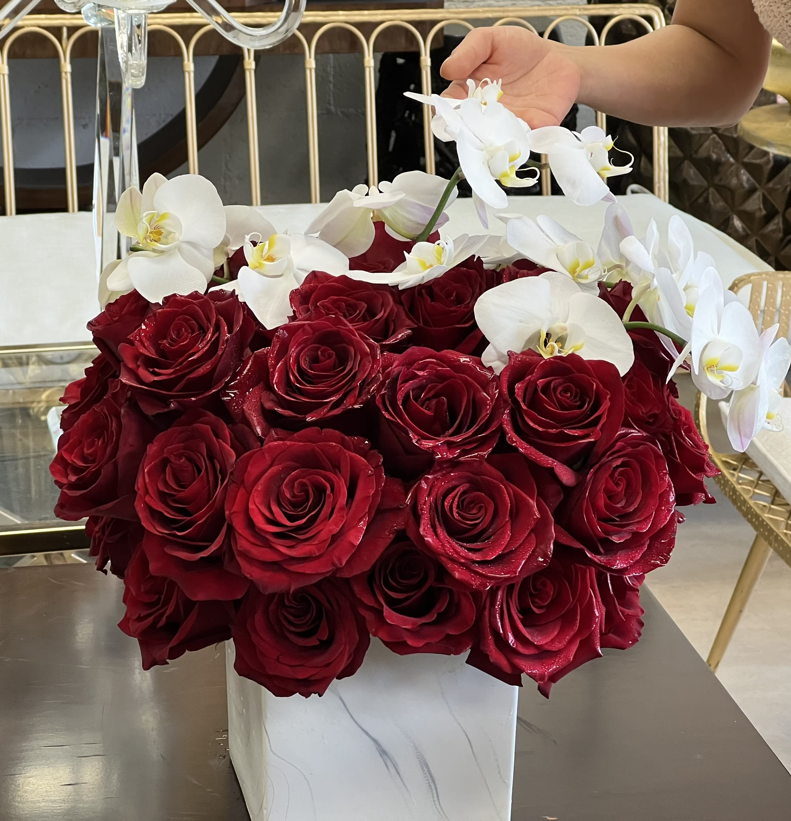 Red roses with white orchids in a white square vase