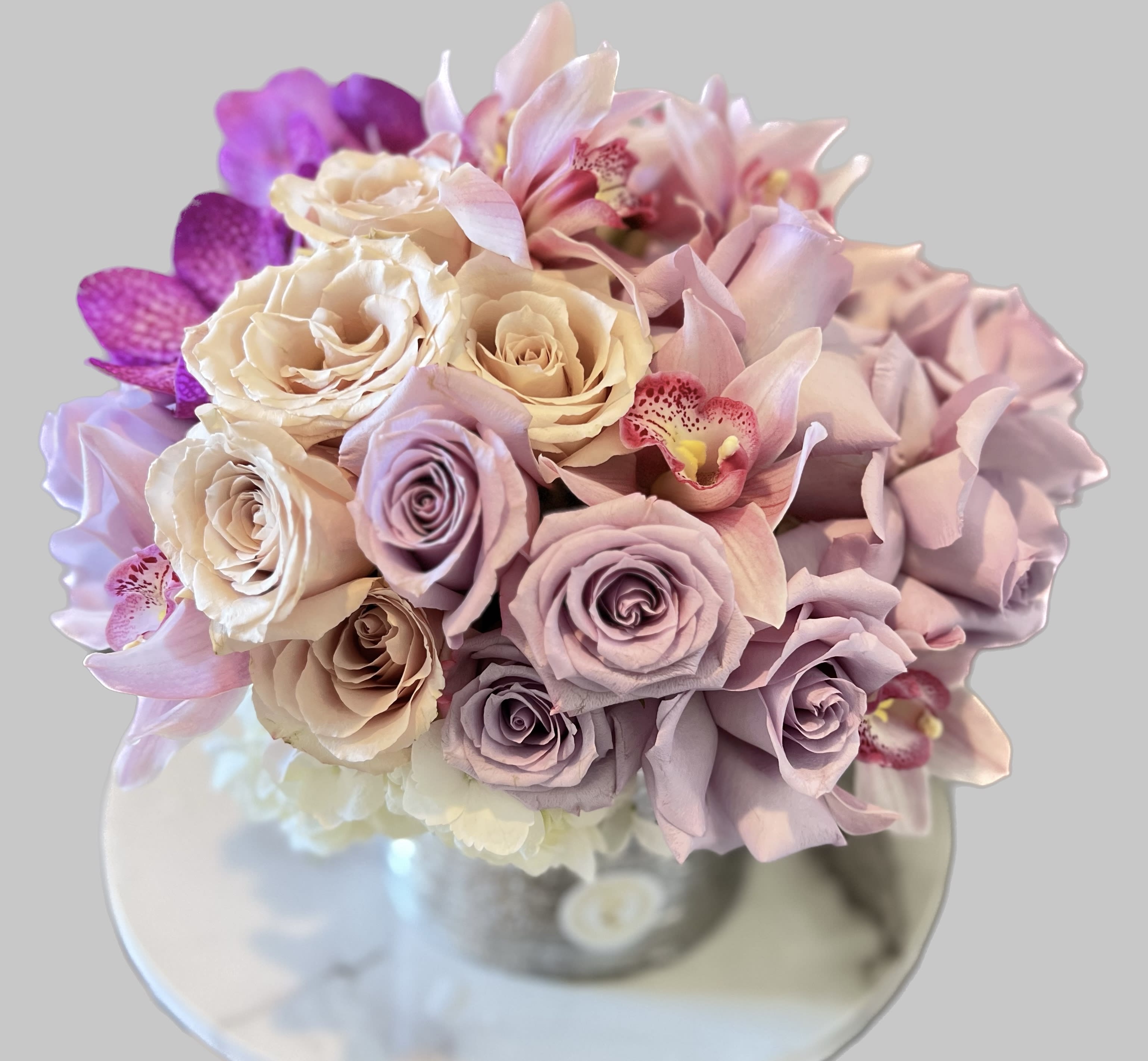 Bouquet of pastel roses and orchids in a clear vase