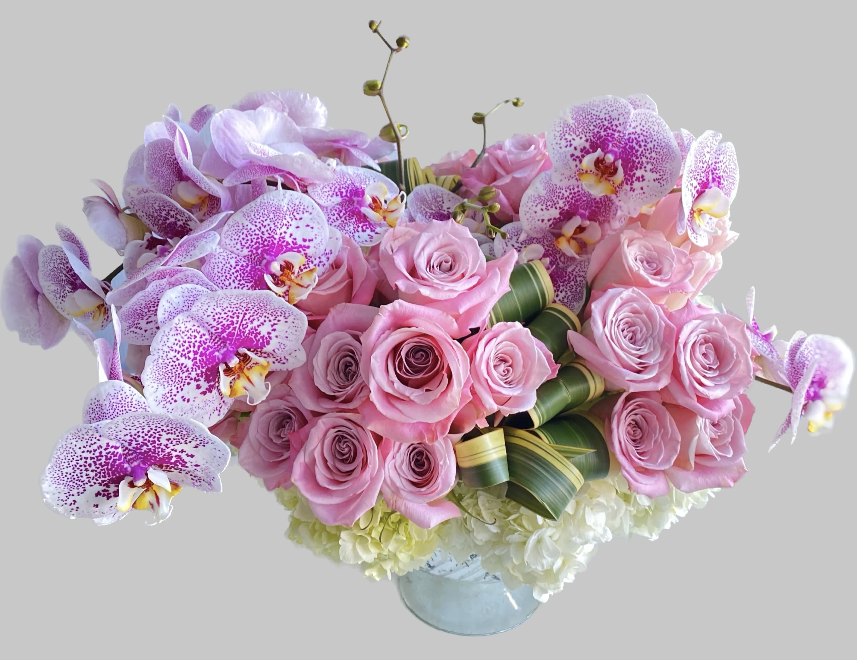Pink roses and speckled orchids in a glass vase