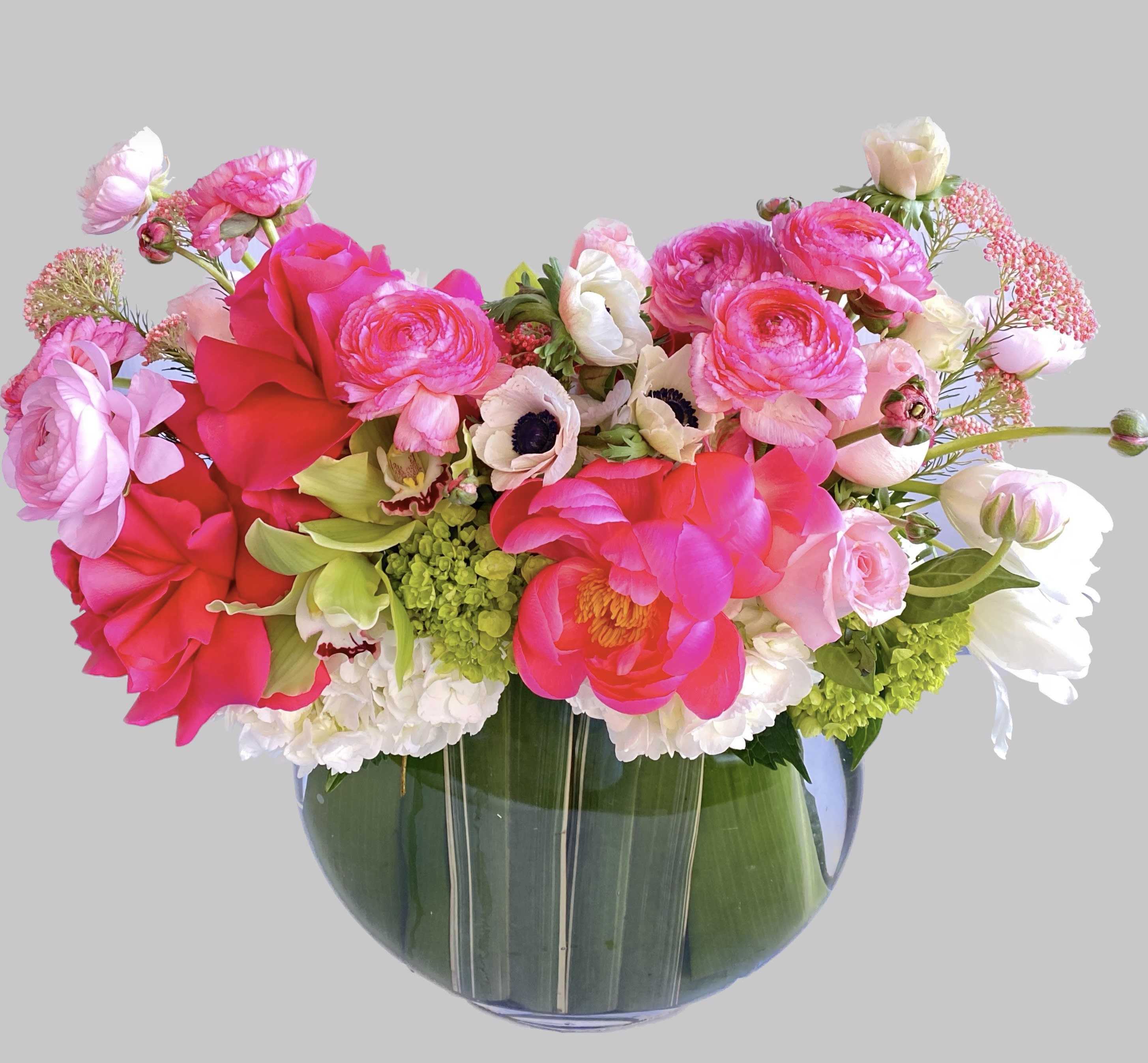 Bright pink and white mixed flowers arranged in a glass vase