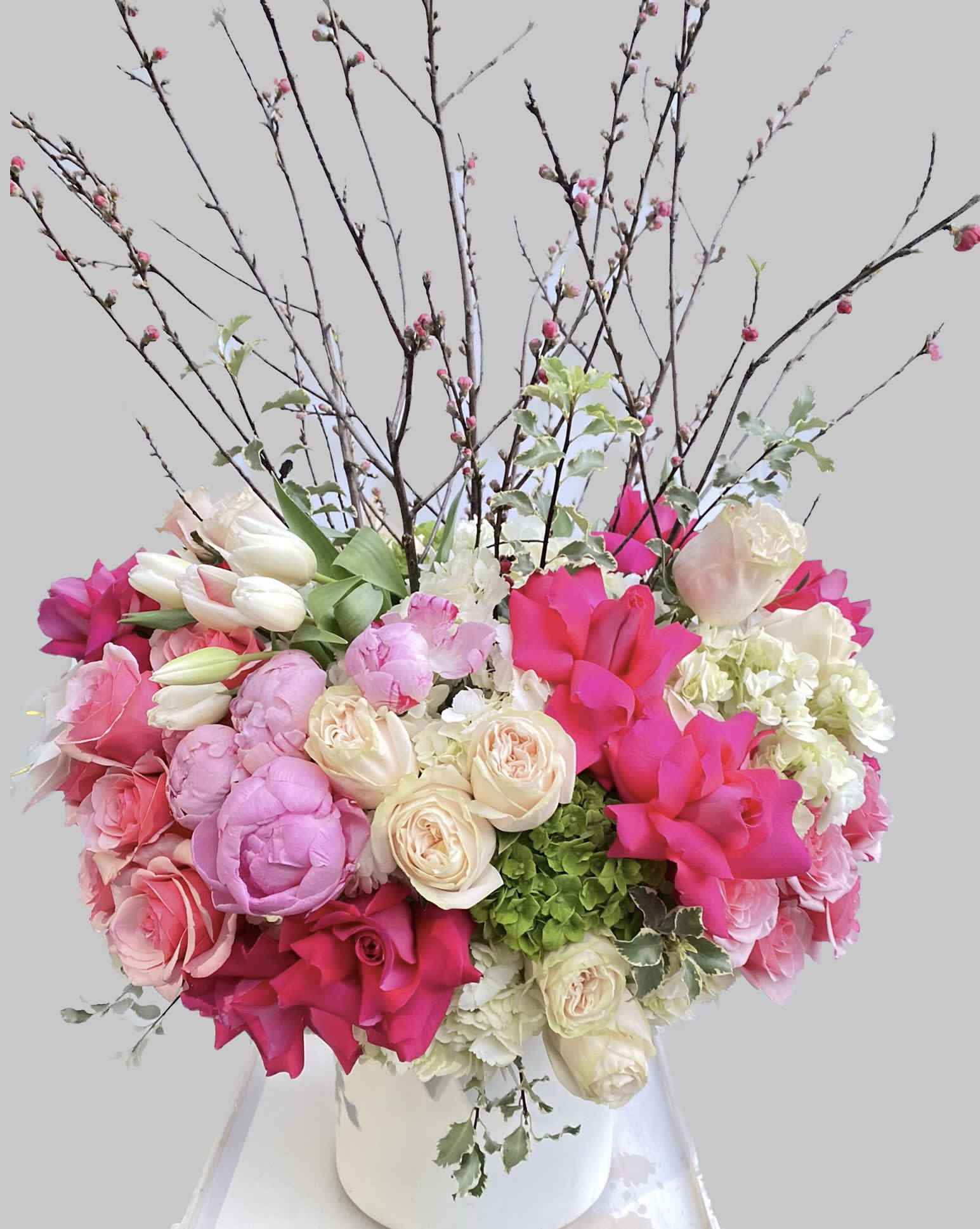 Pink and white floral arrangement in a white vase with tall branches