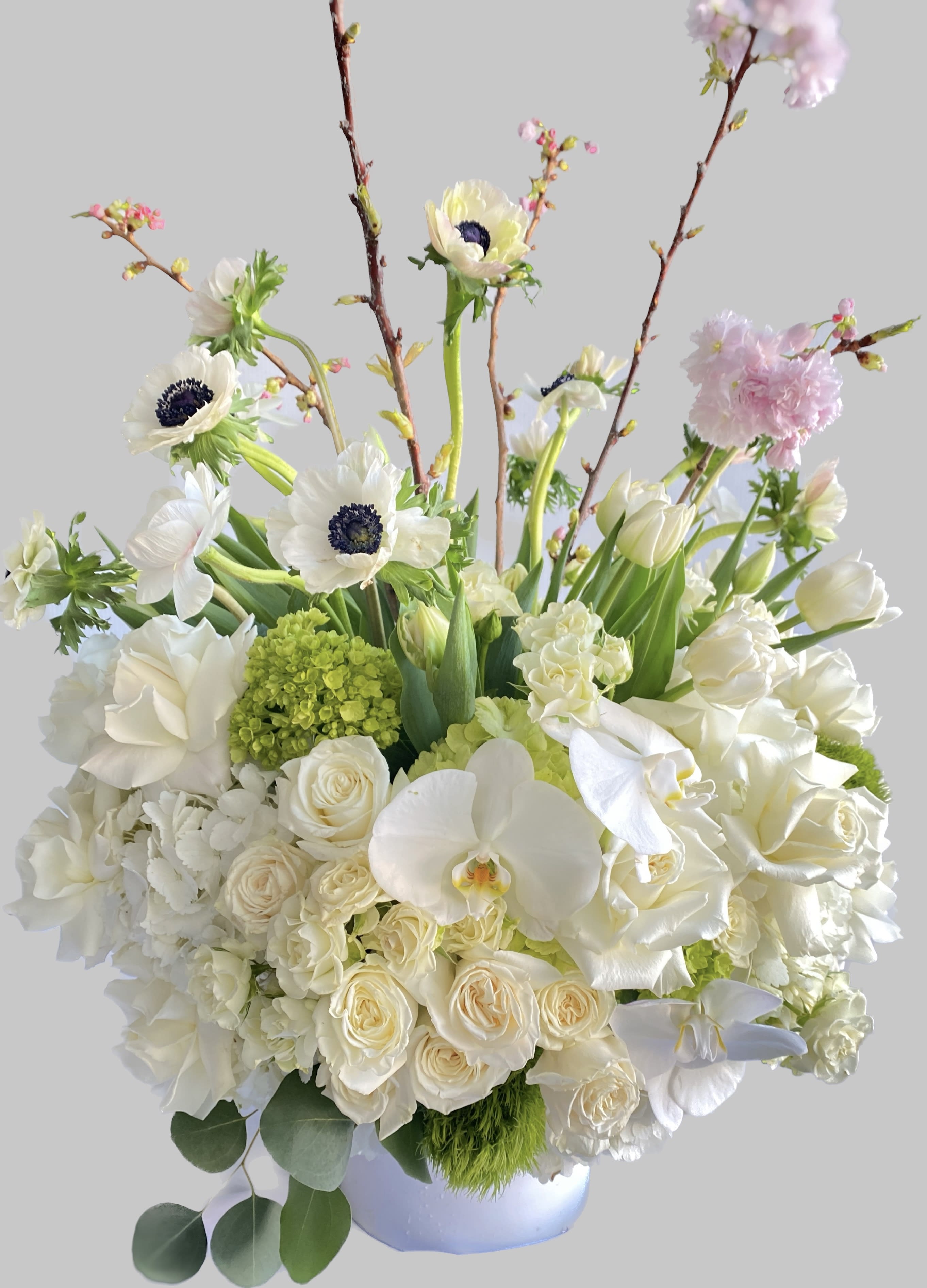 White floral arrangement with orchids, roses, and tulips in a vase