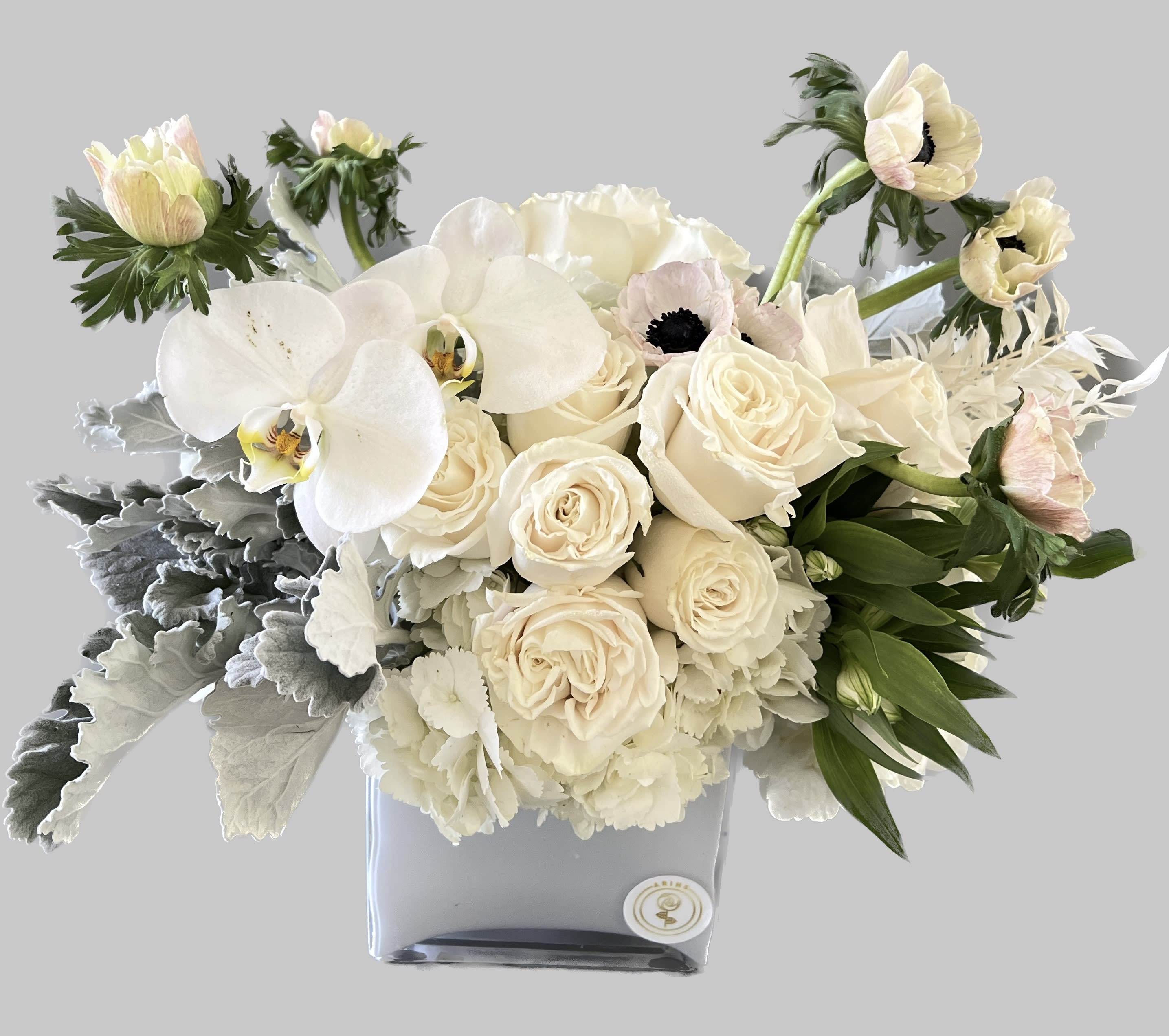 Cream roses and white orchids in a square vase