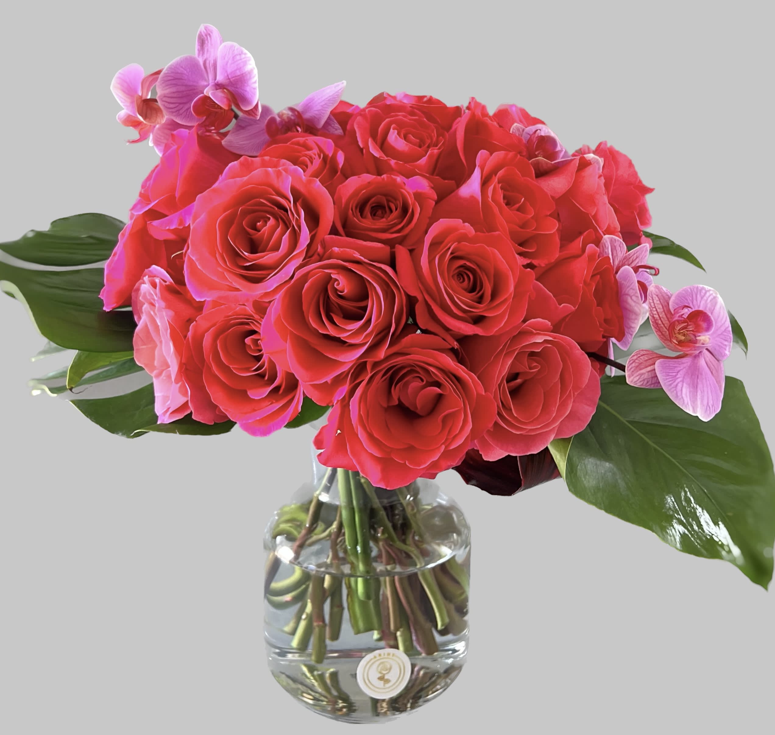 Pink roses with orchid accents in a clear glass vase