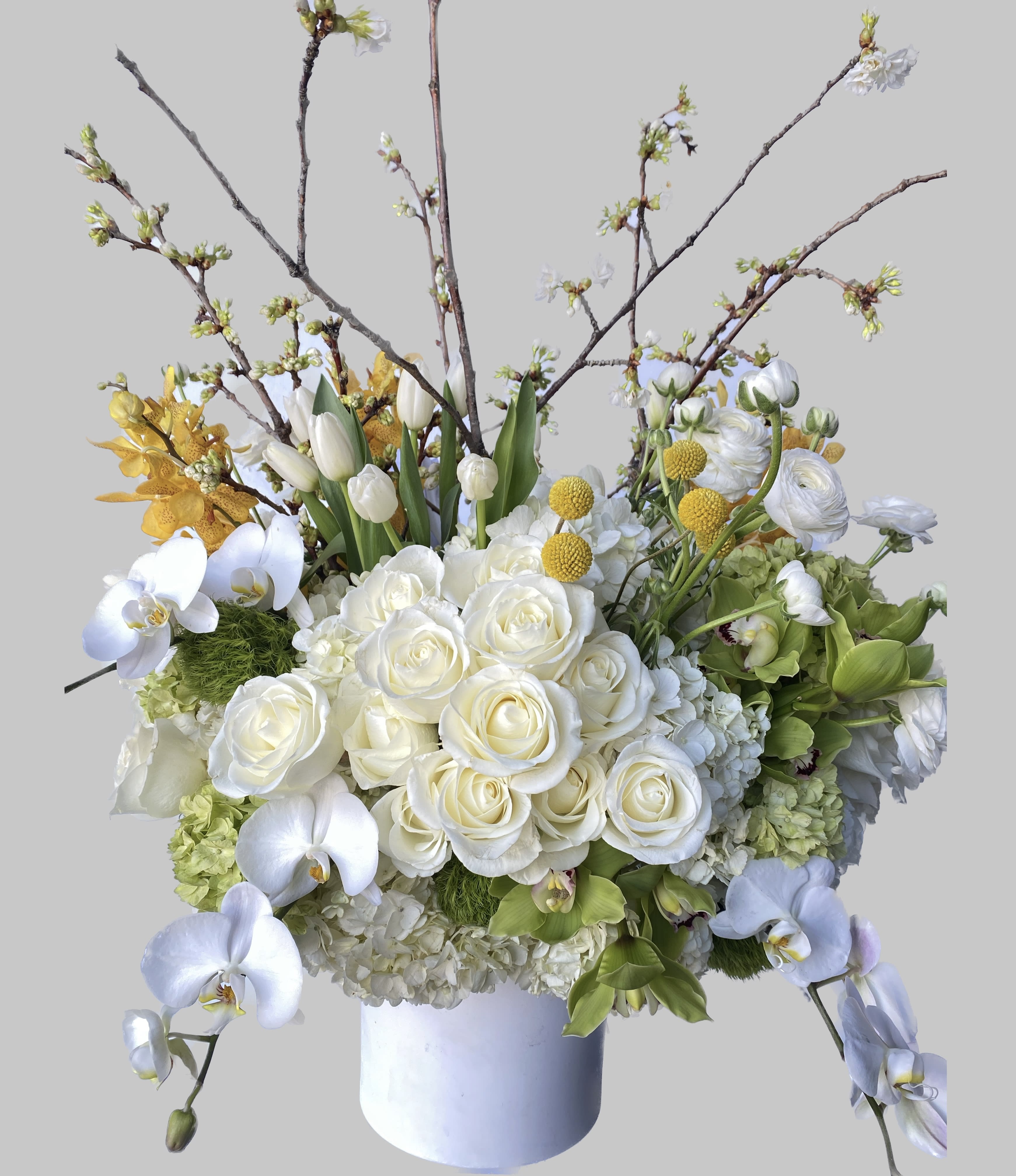 White roses, orchids, and tulips in a white vase