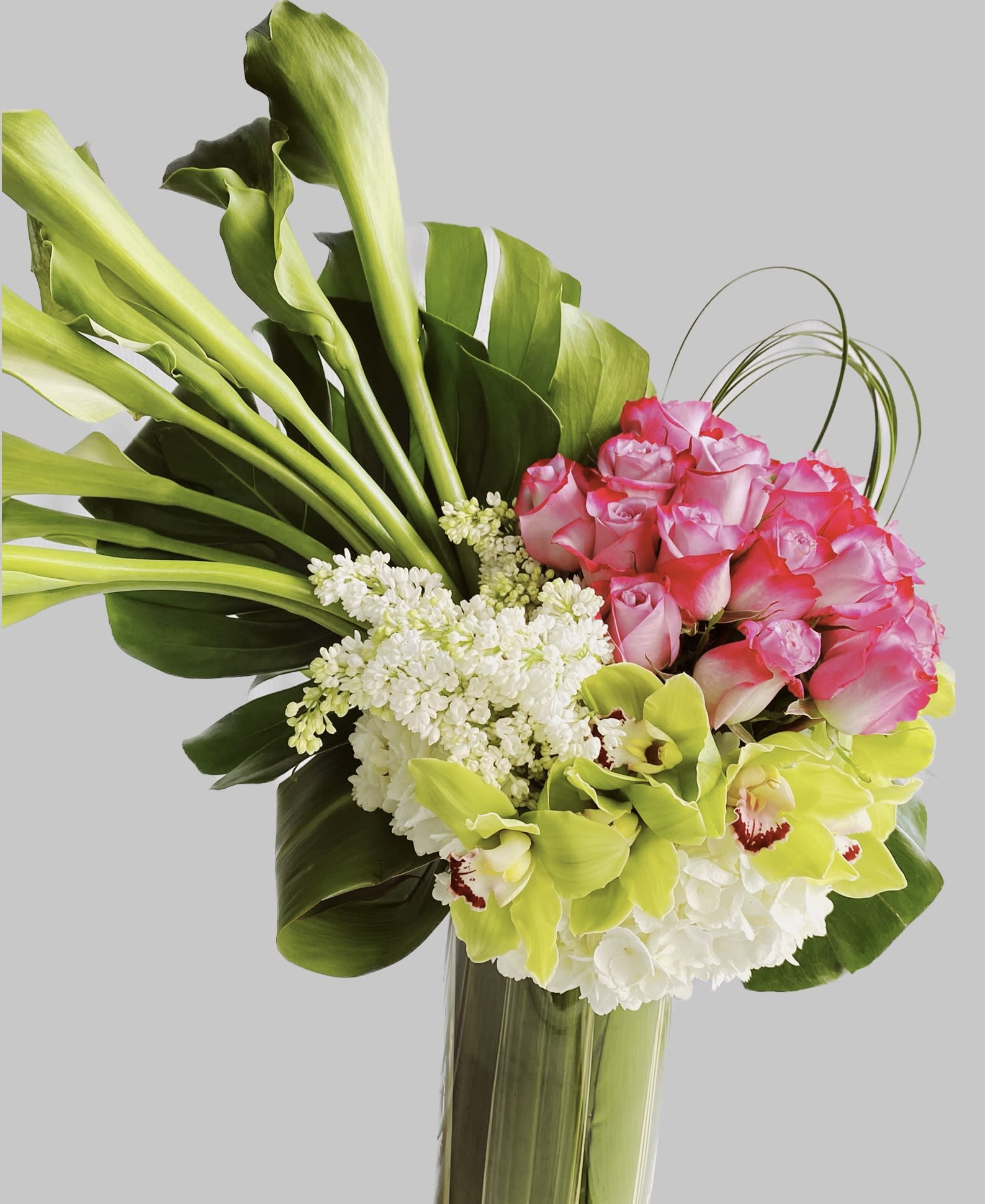 Bouquet of pink roses, green orchids, and white flowers in a tall vase
