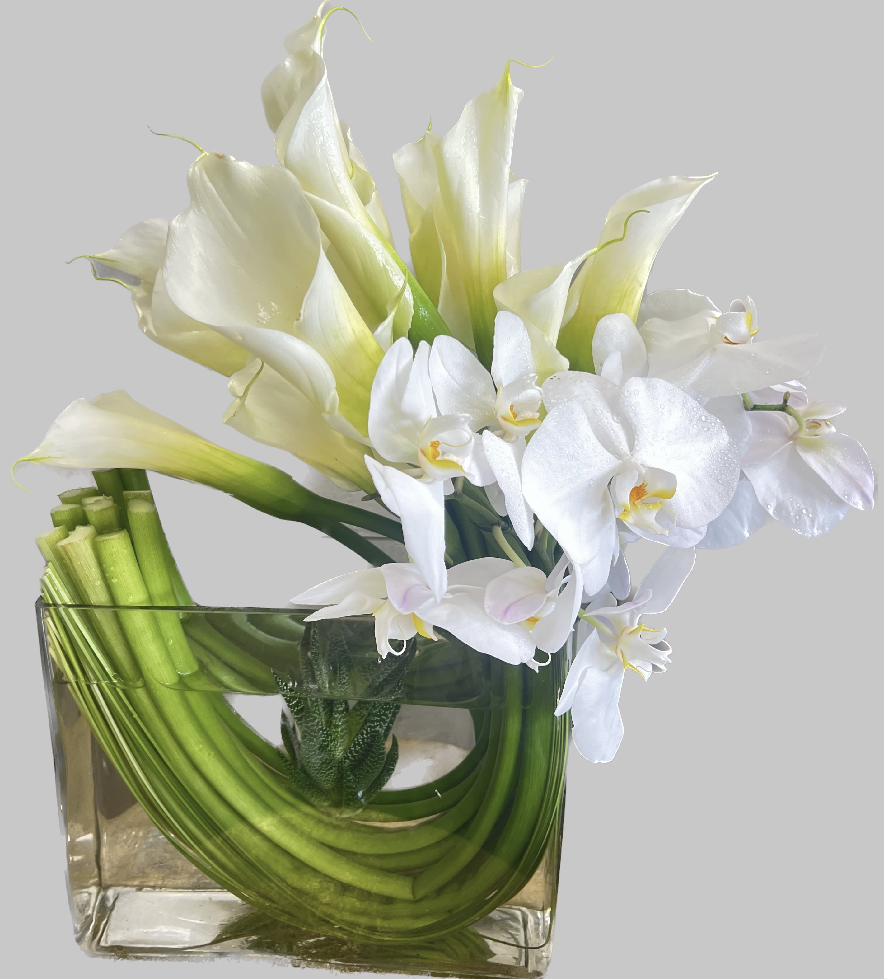 White calla lilies and orchids in a square glass vase