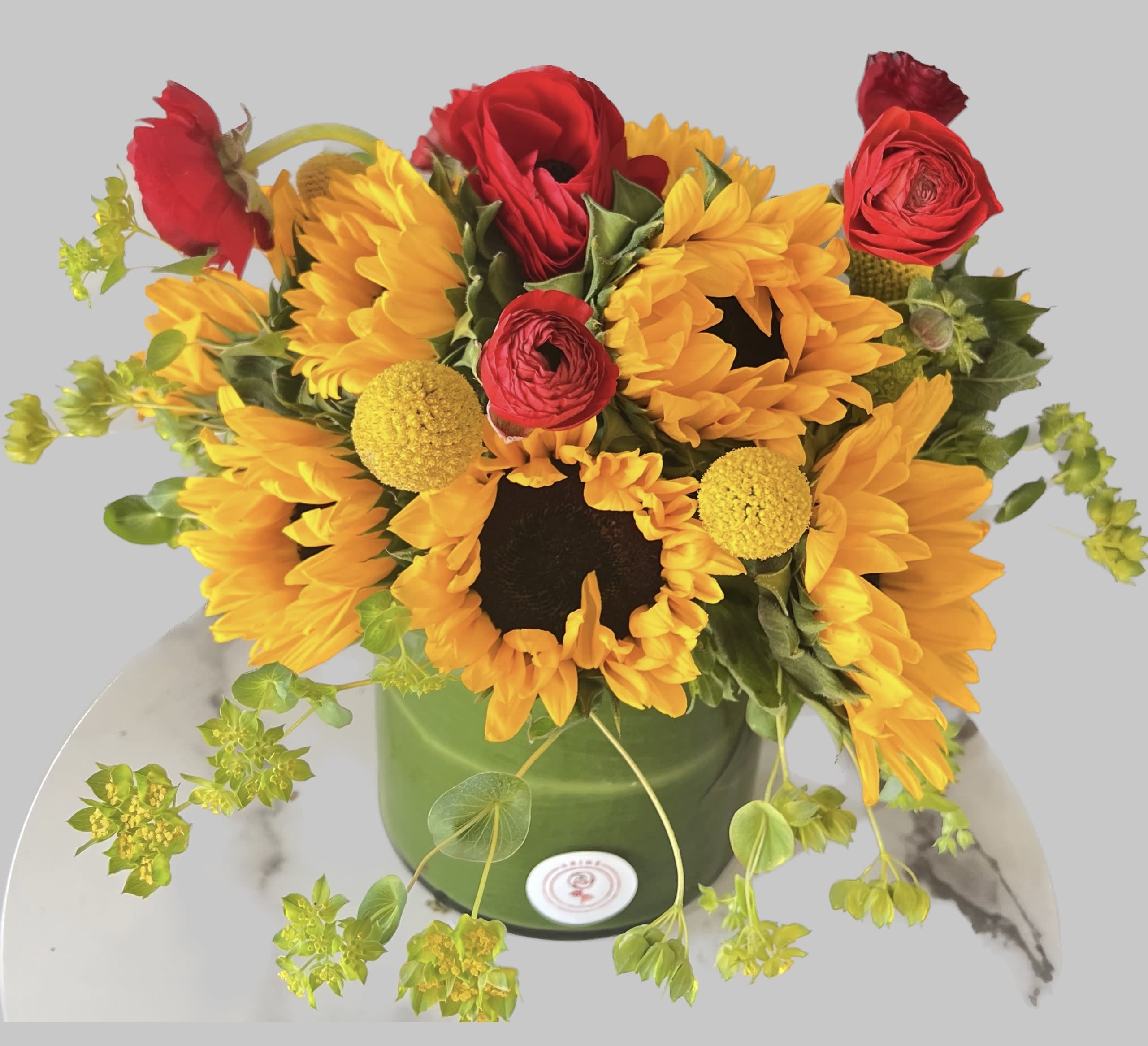 Sunflower and red rose arrangement in a green container