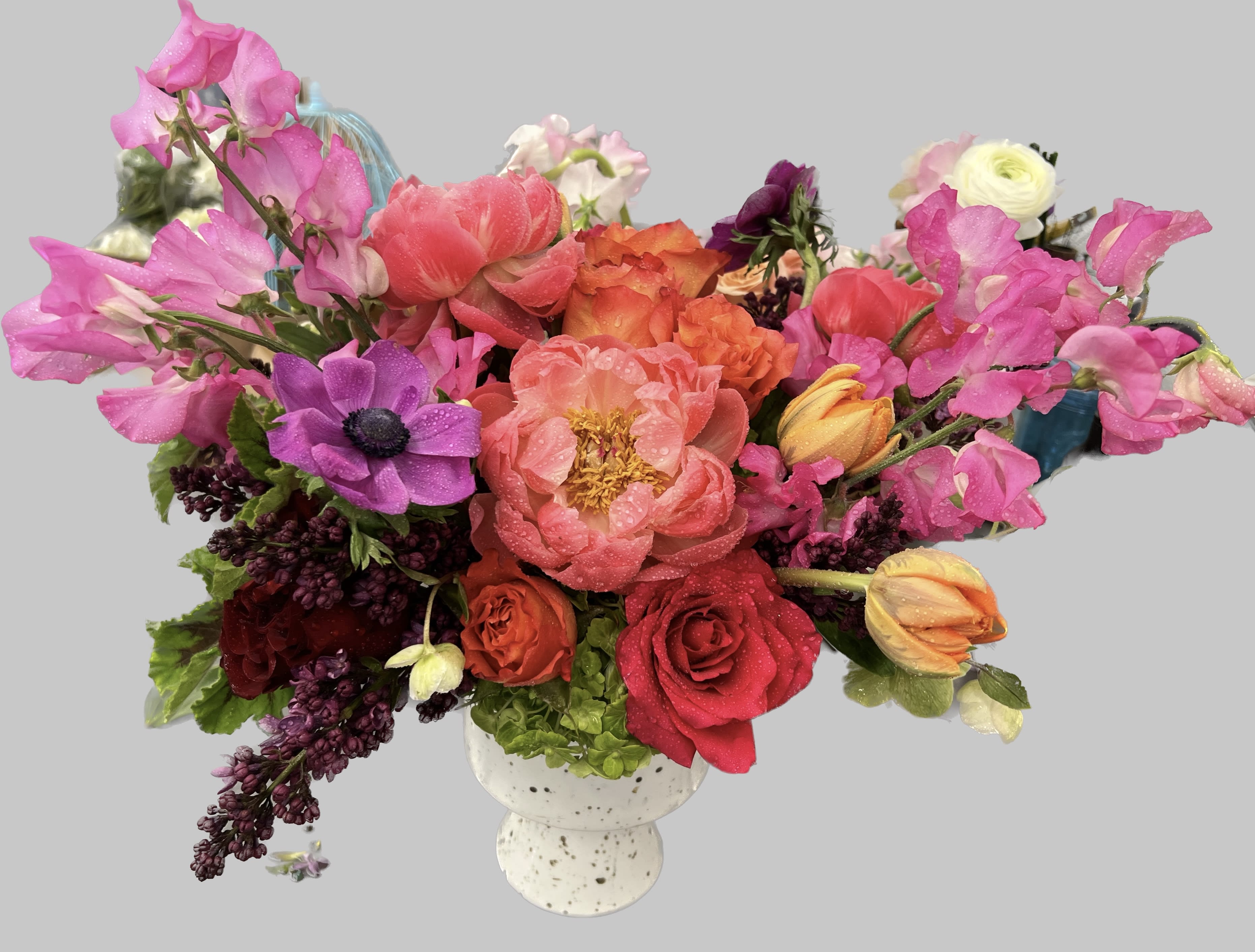 Mixed bouquet of pink, red, orange, and purple flowers in a white vase