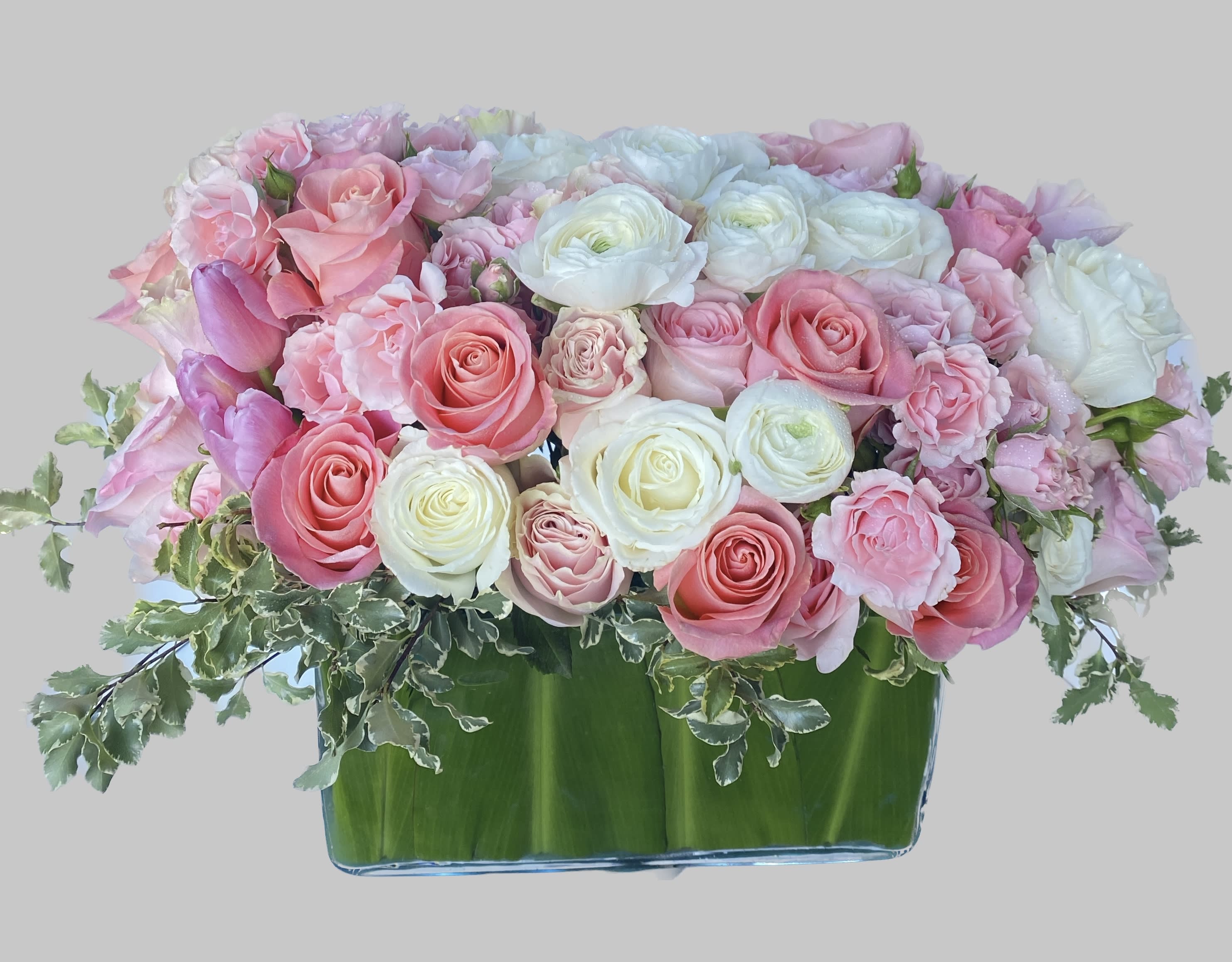 Pink and white roses arranged in a low glass vase