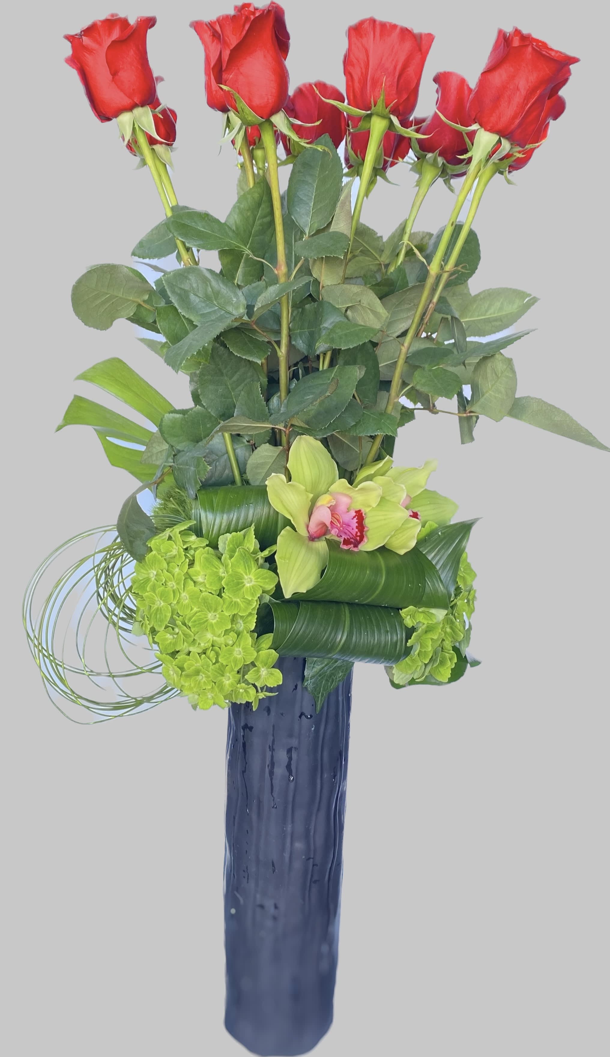 Tall arrangement of red roses and green orchids in a blue vase