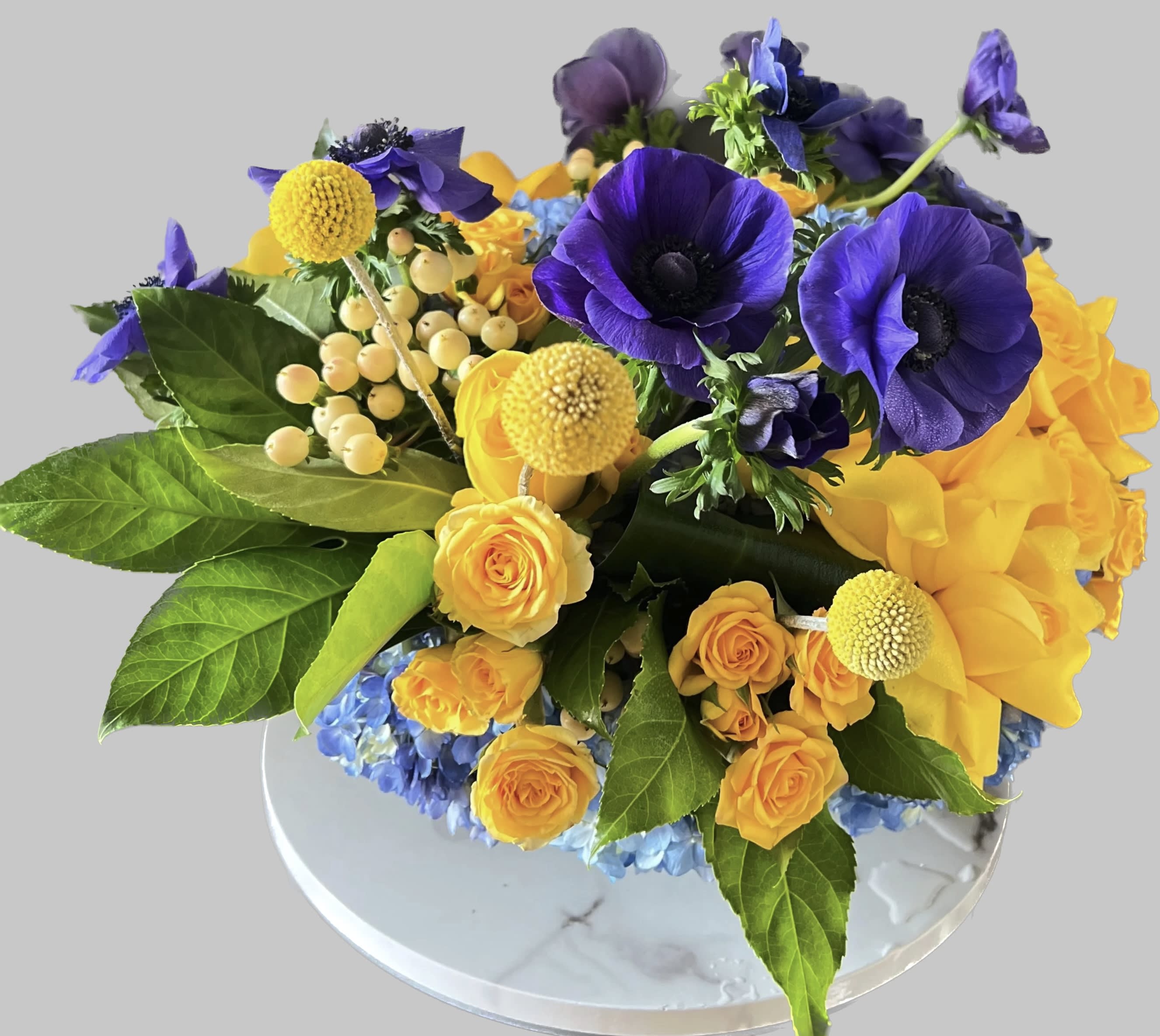 Purple anemones and yellow roses in a low round arrangement