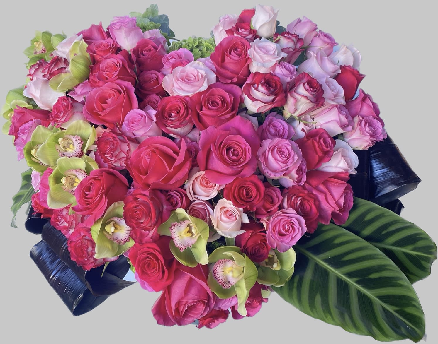 Heart-shaped bouquet of pink roses with green orchids and dark leaves