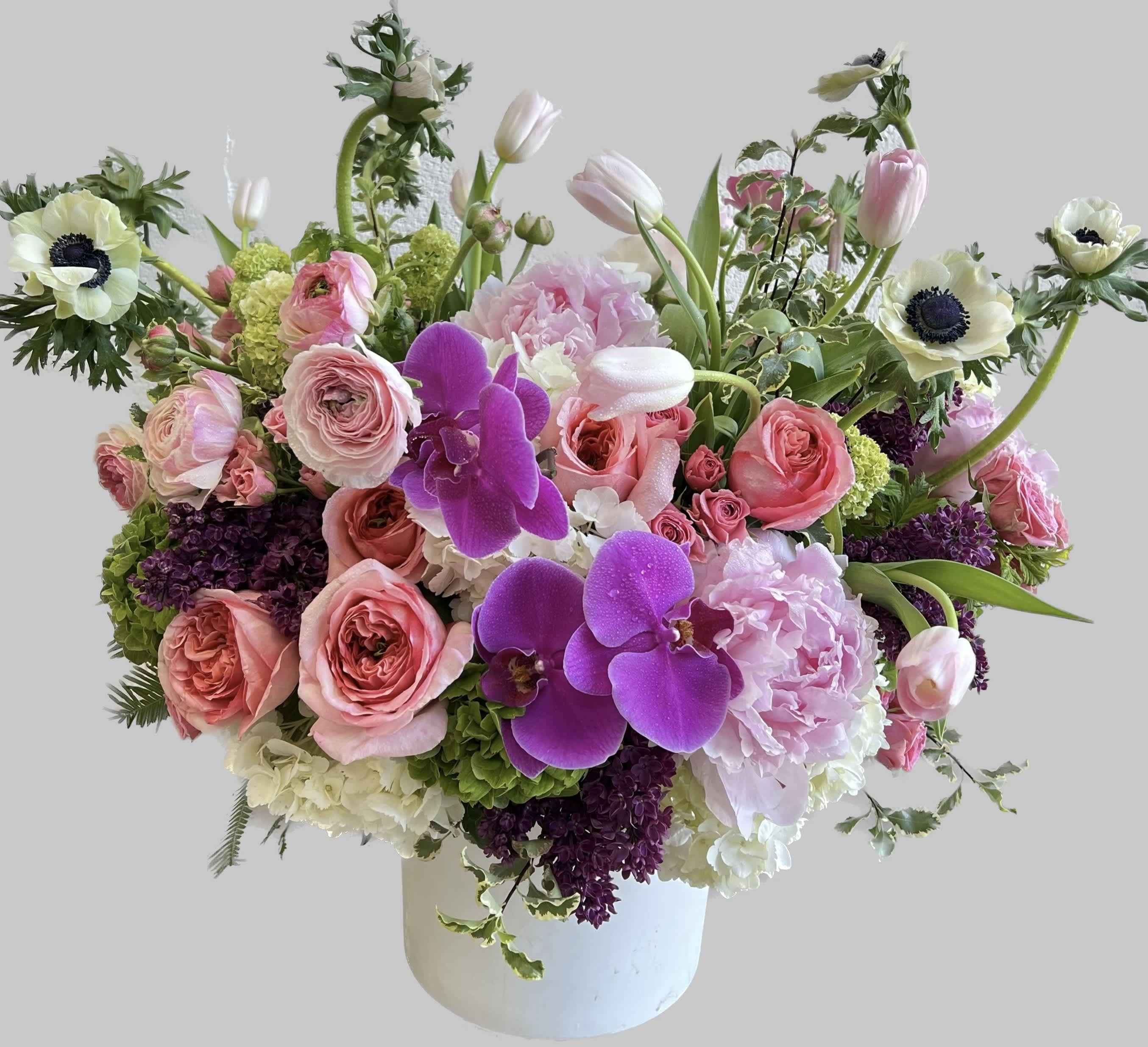 Pink and white floral arrangement with orchids and roses in a white vase