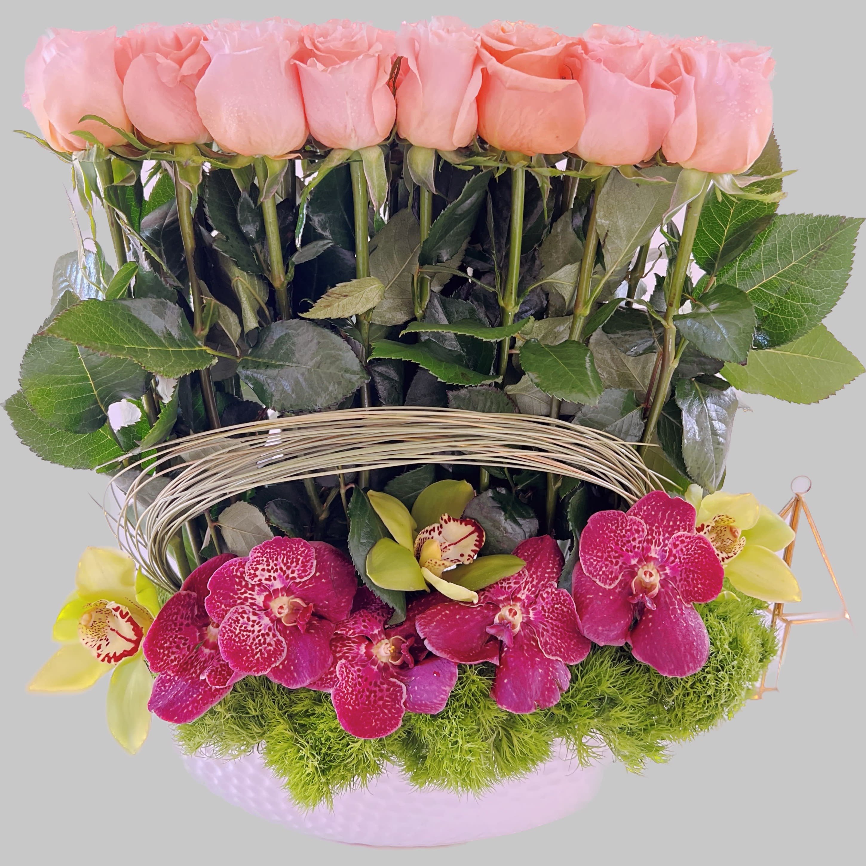 Pink roses and magenta orchids arranged in a basket with moss.