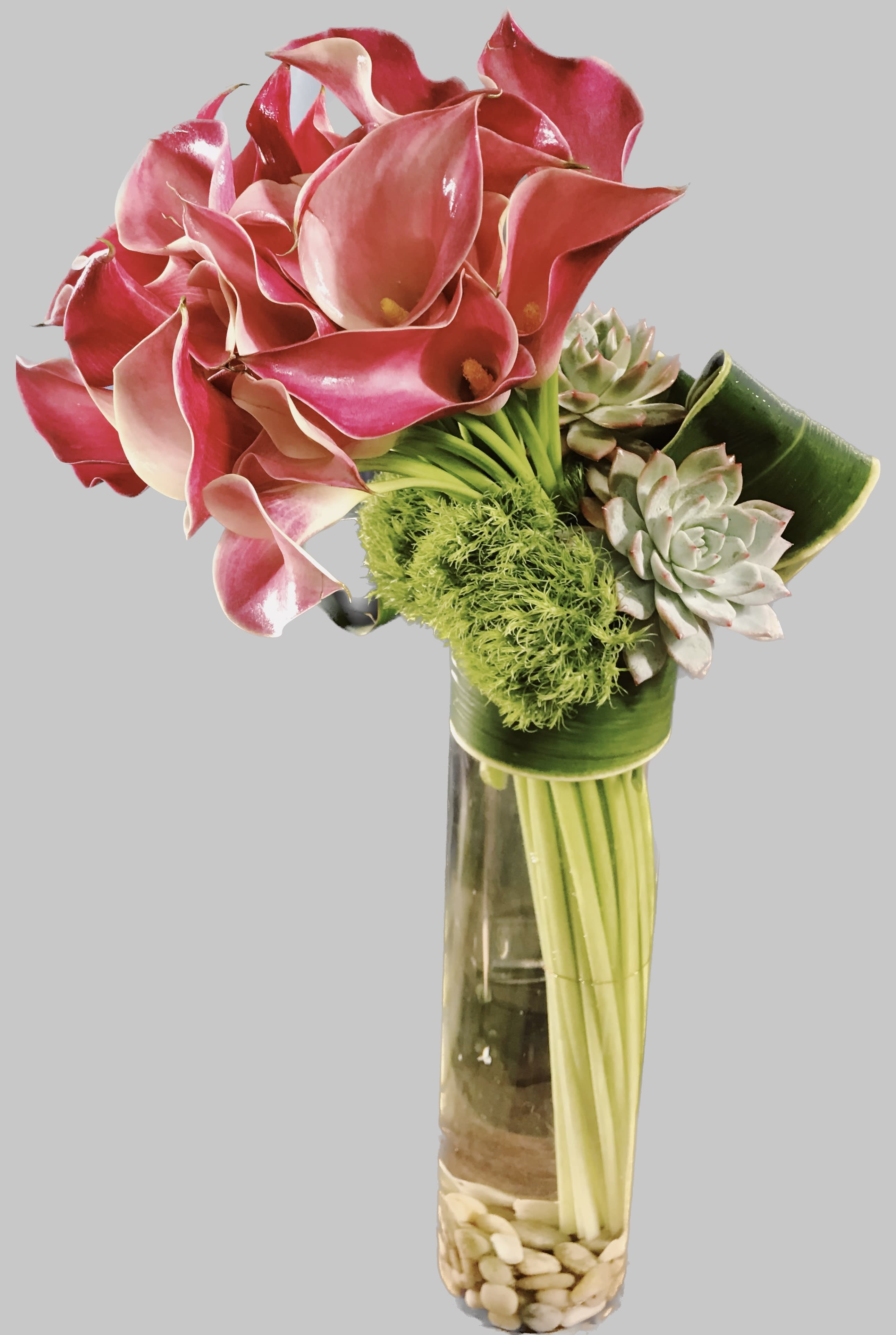 Pink calla lilies and succulents in a tall glass vase
