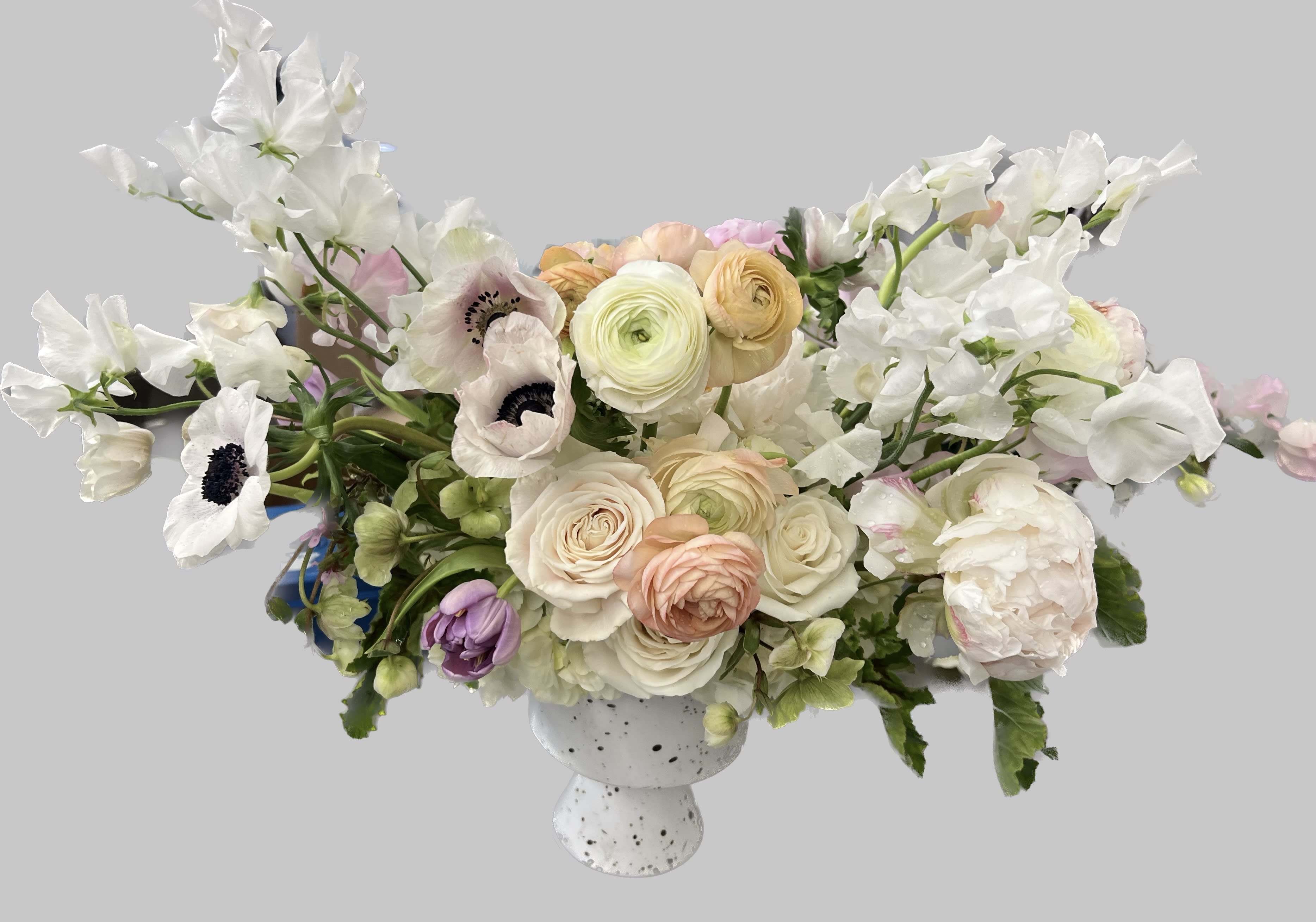 White and blush floral arrangement in a speckled pedestal vase