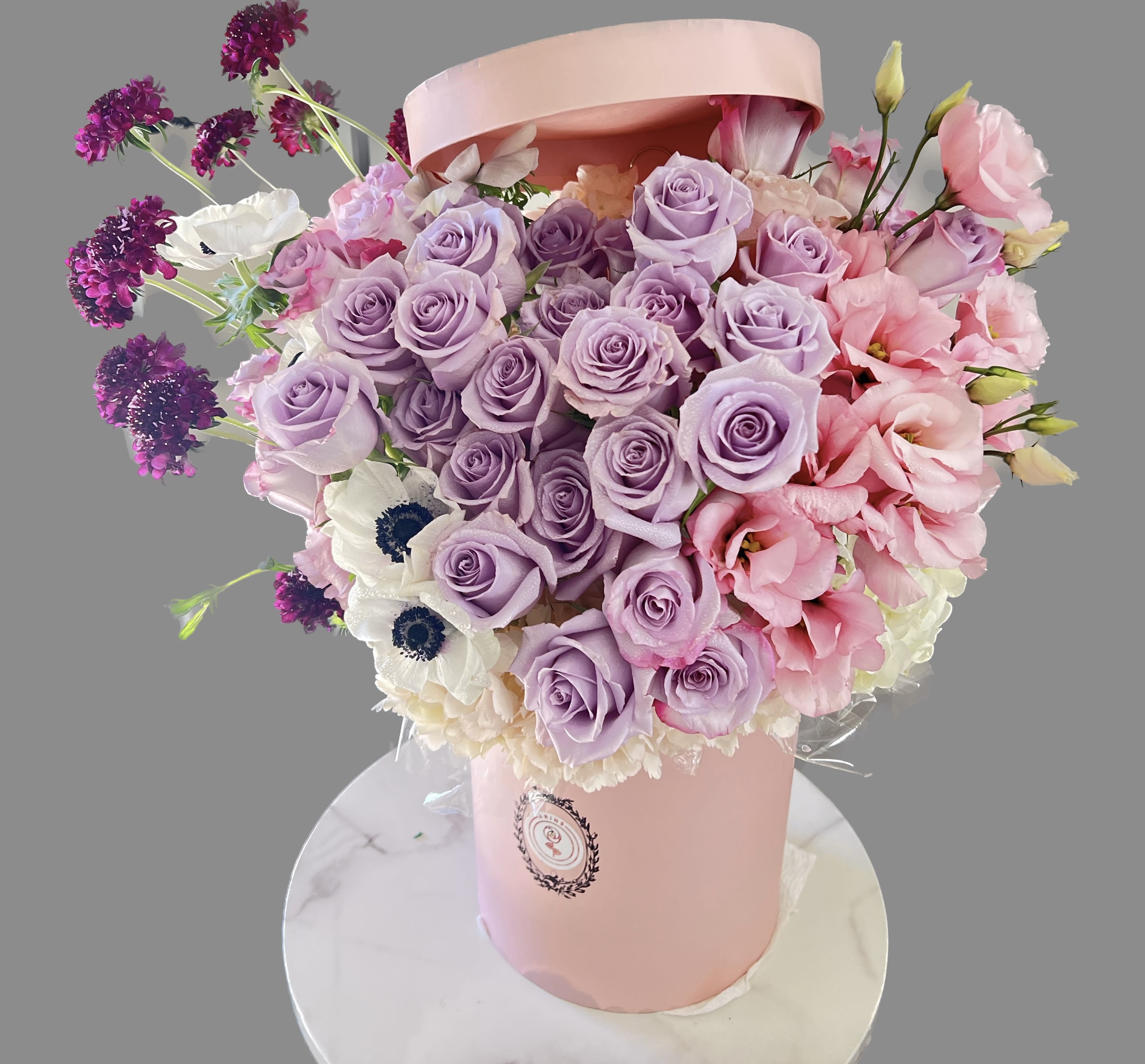 Lavender and pink rose bouquet in a pink hatbox with white flowers