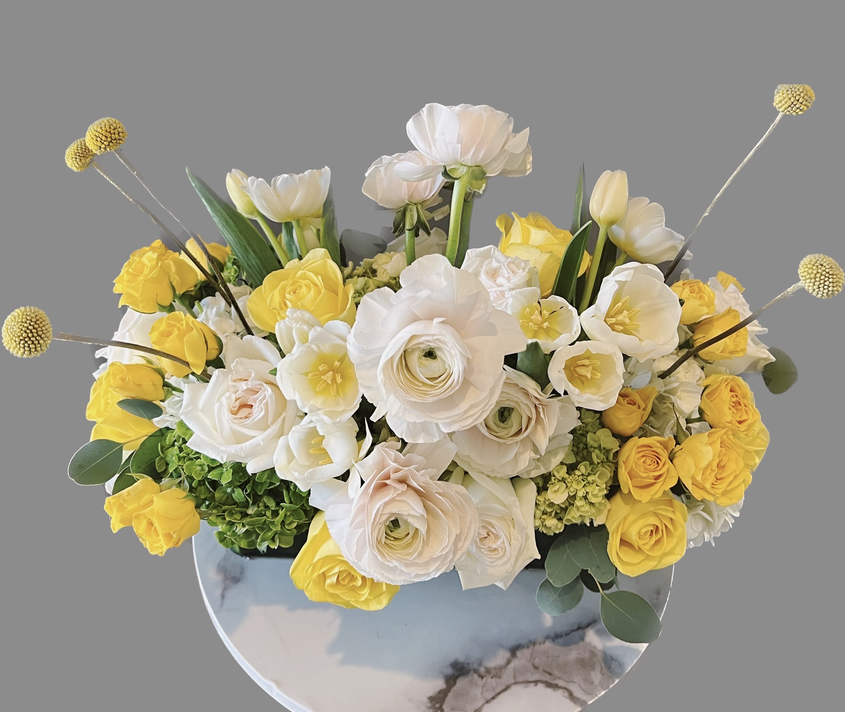 Yellow and white floral arrangement in a round vase