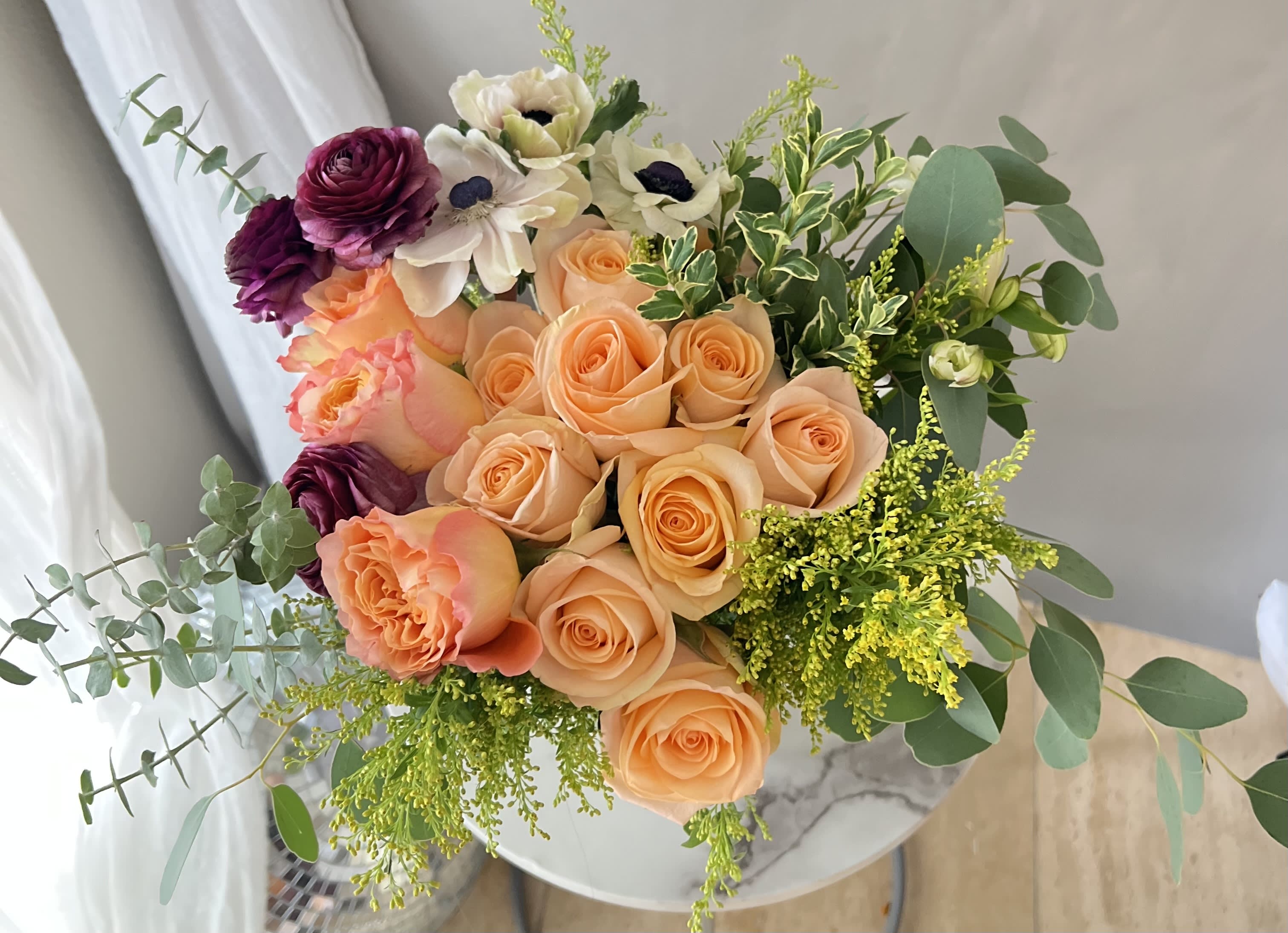 Bouquet of peach and purple roses with white flowers and greenery