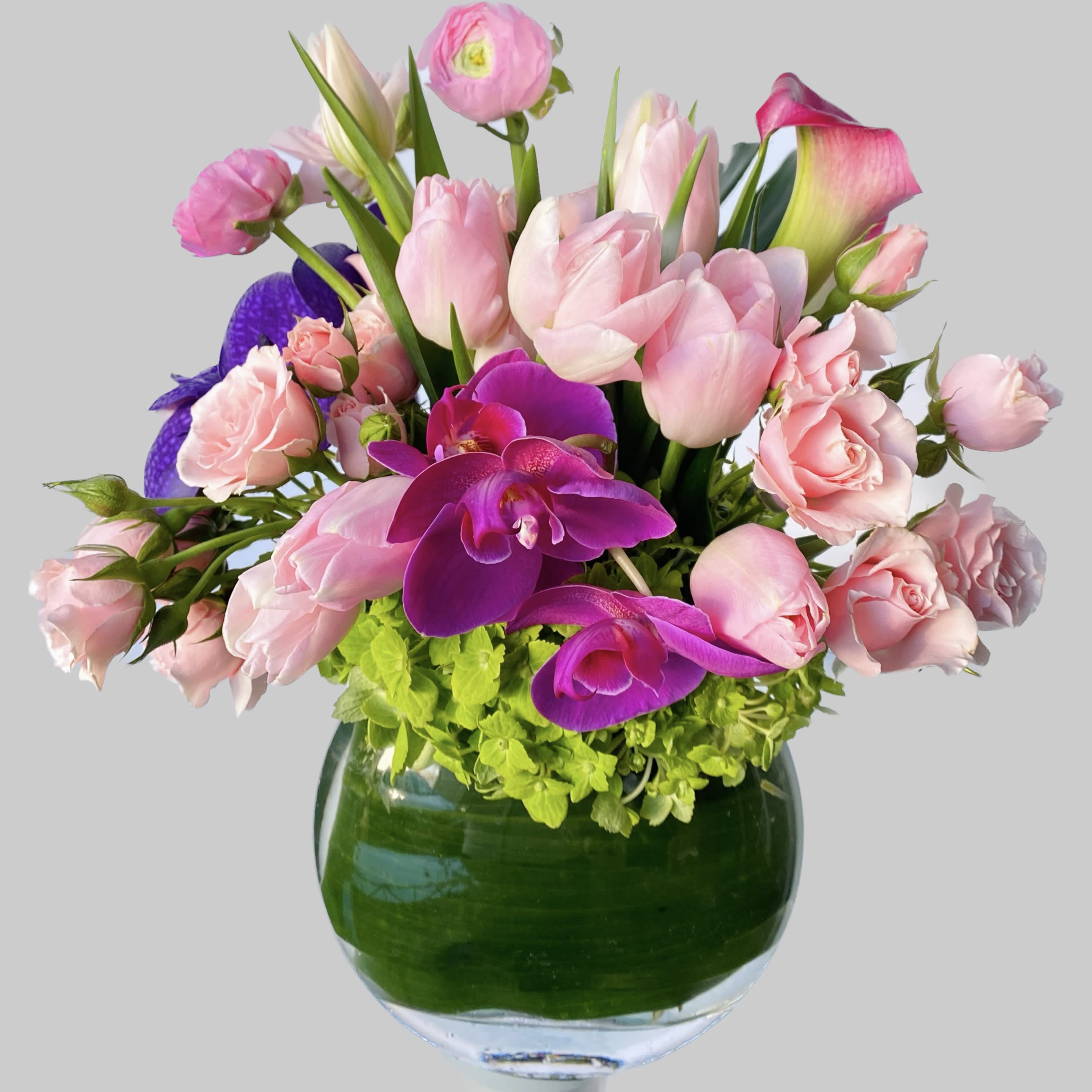 Pink tulips, roses, and purple orchids in a glass vase