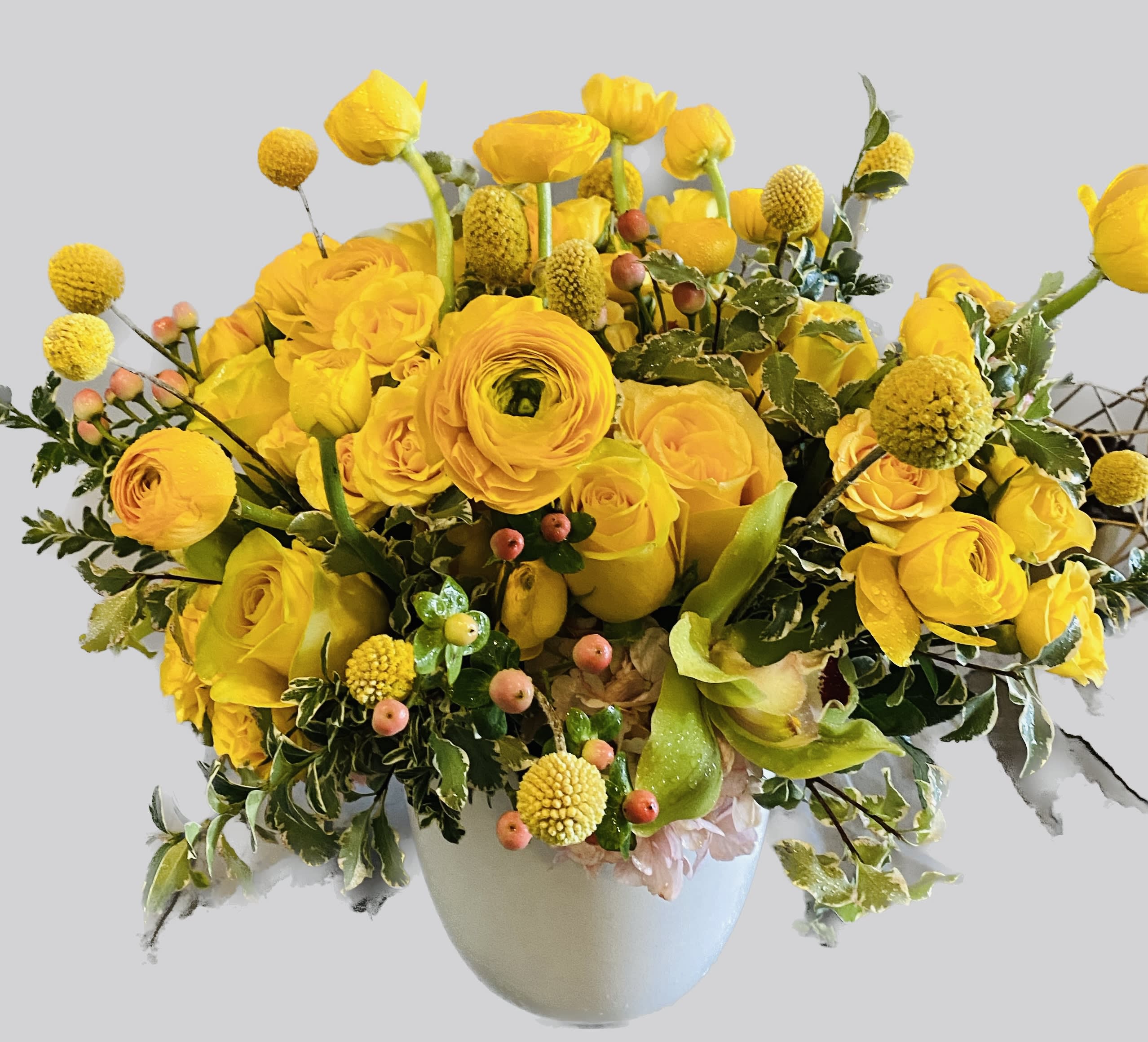 Yellow floral arrangement in a white vase with round blooms and berries