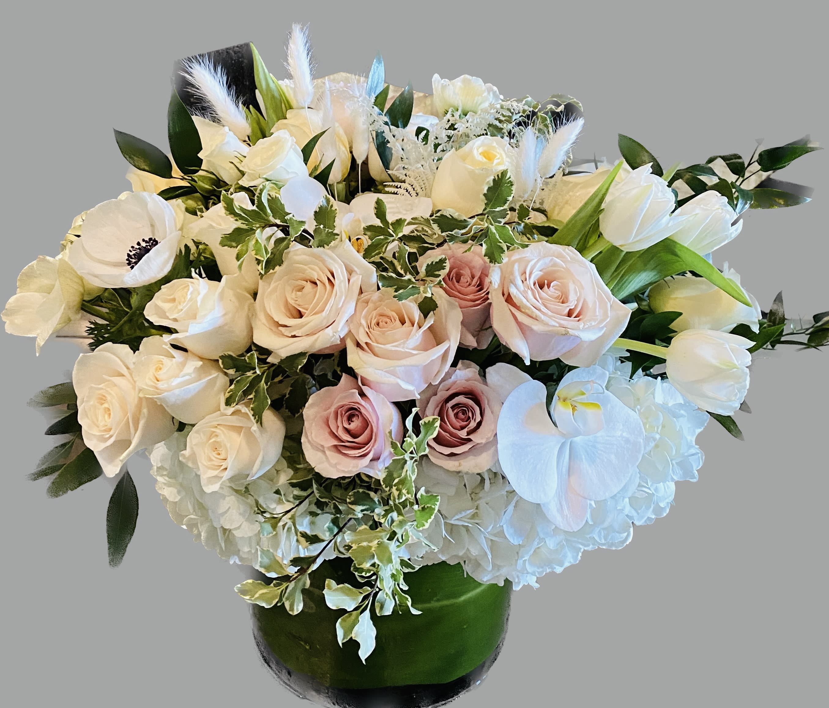 Bouquet of white and blush roses with white orchids in a green vase