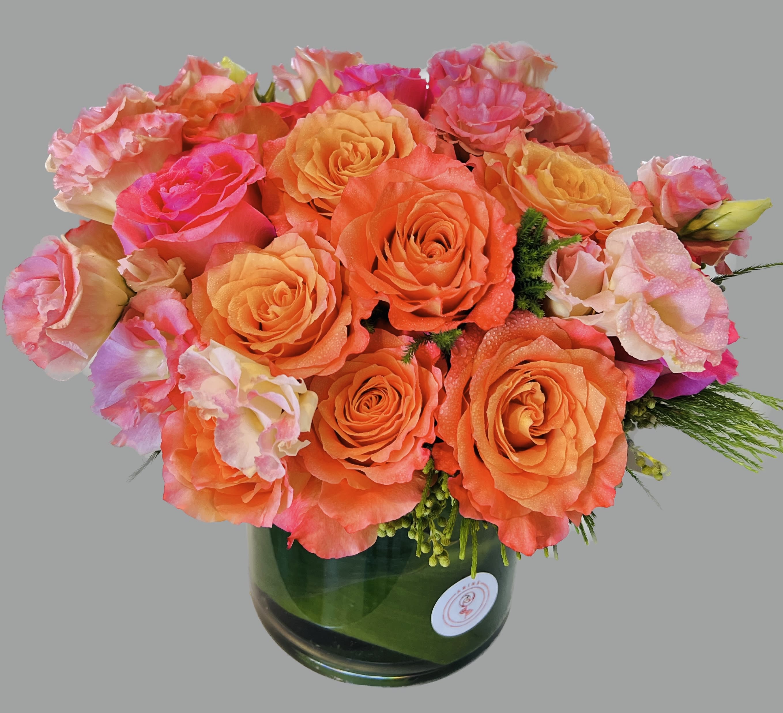Bouquet of orange and pink roses in a green glass vase