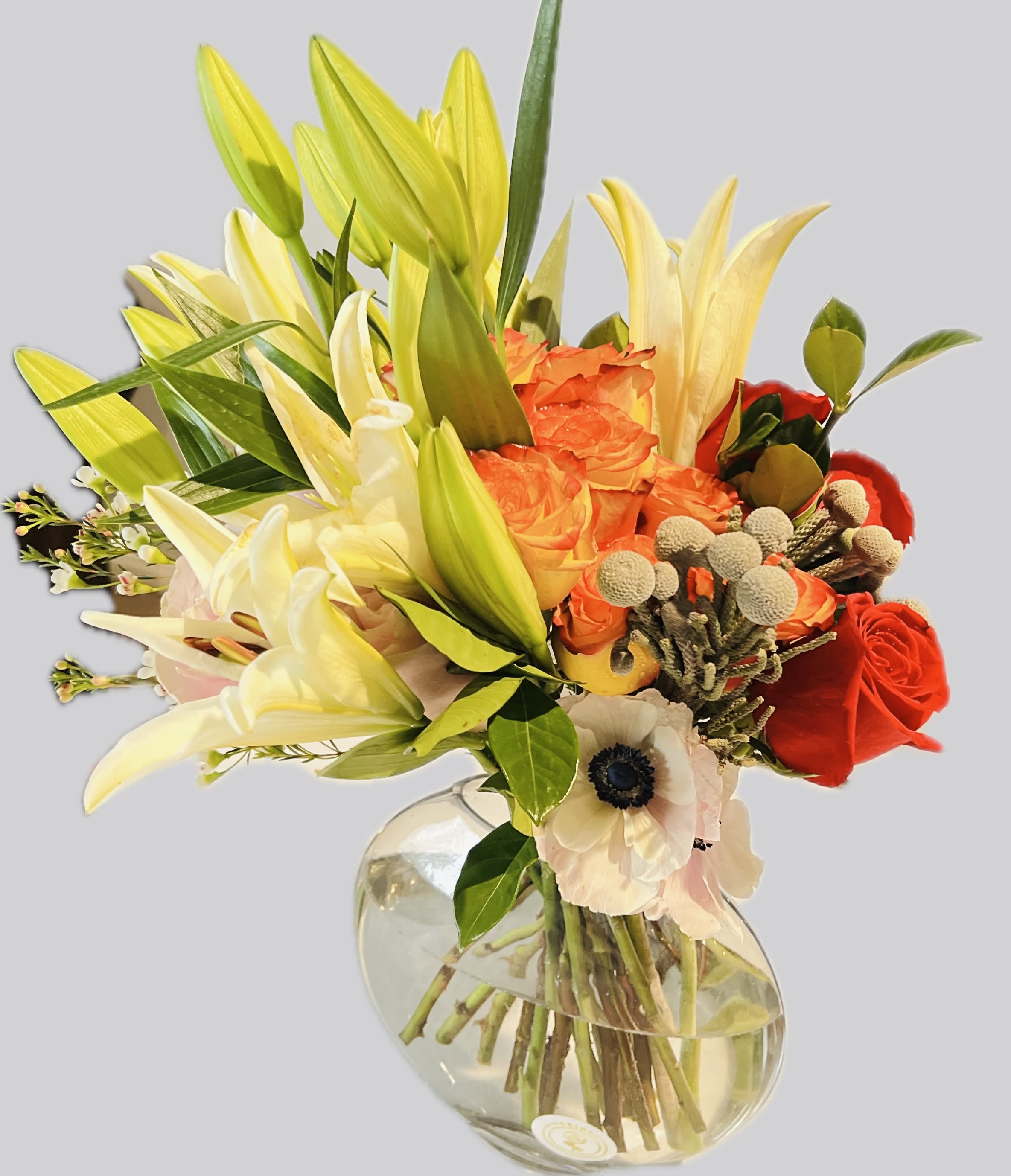 Bouquet of lilies, roses, and anemones in a clear glass vase