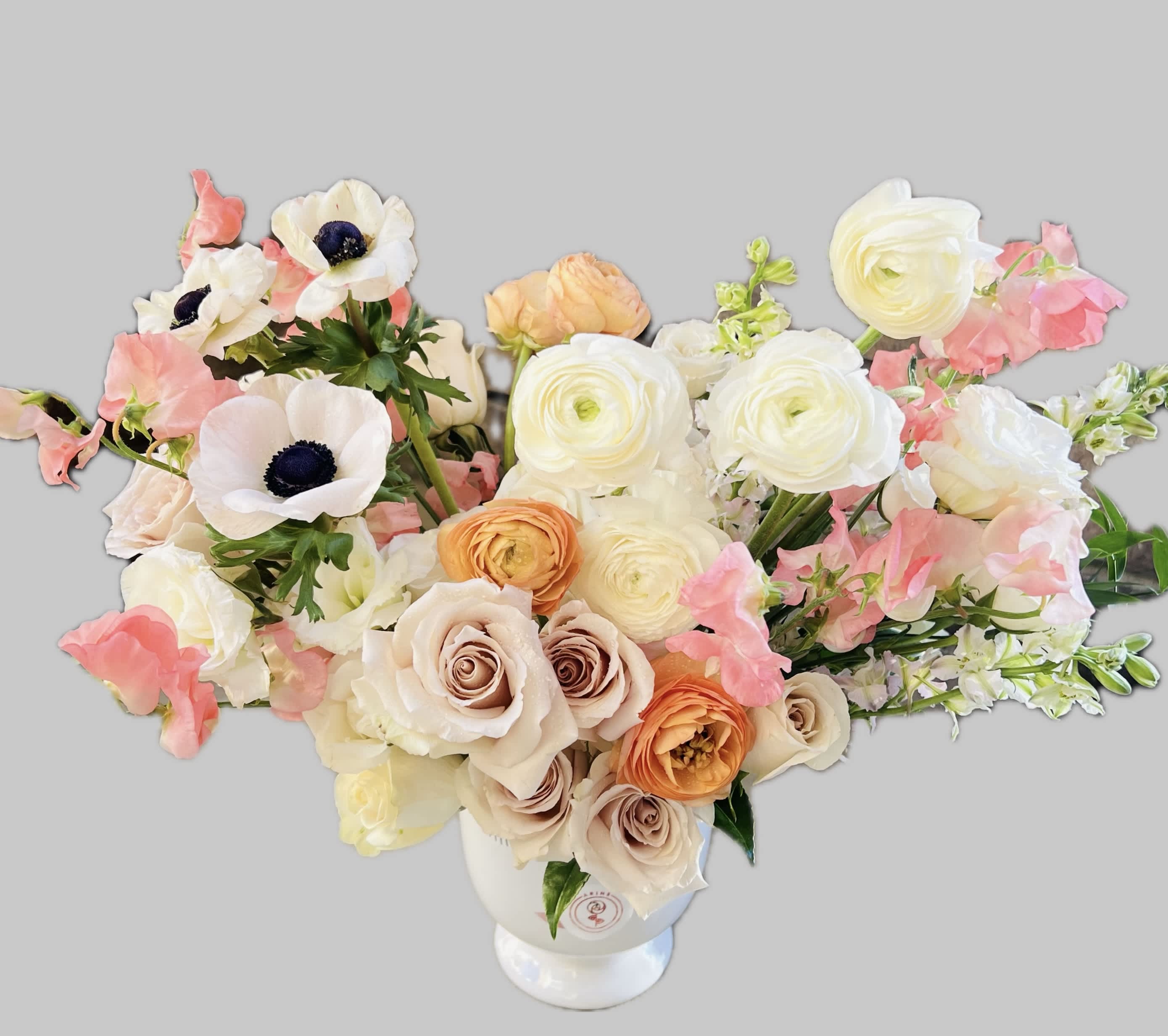 Bouquet of cream, peach, and pink flowers in a white vase