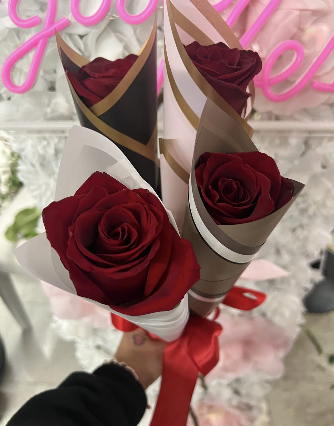 Three red roses wrapped in decorative paper with a red ribbon