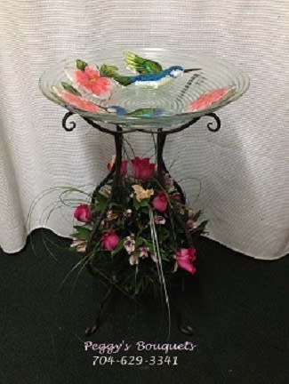 Glass birdbath with pink flowers and a floral base arrangement
