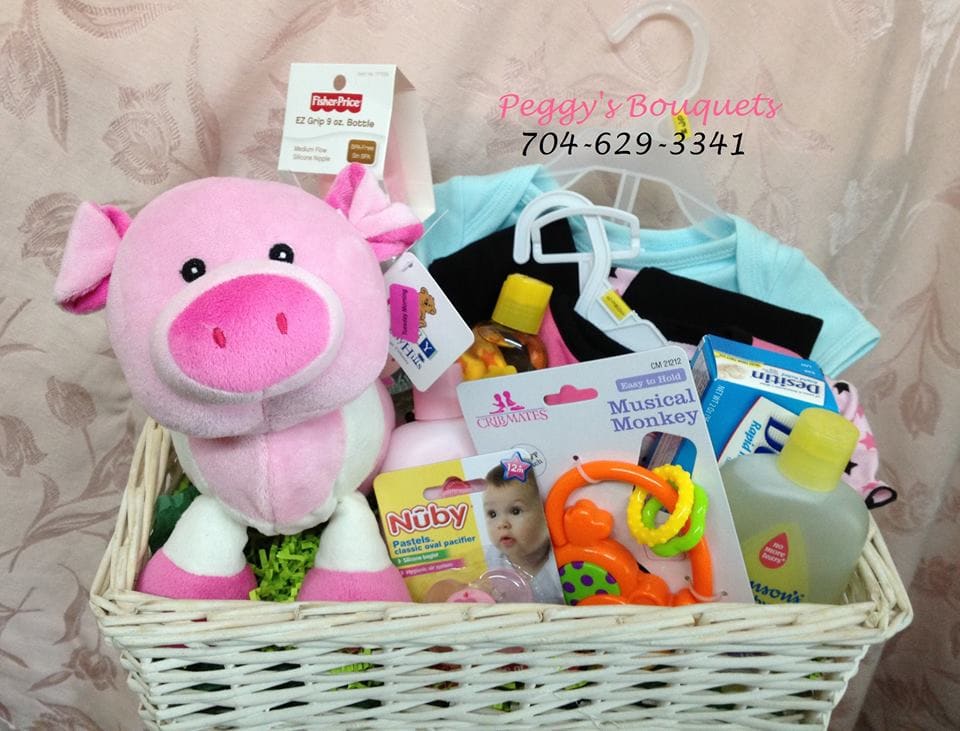 Gift basket with a pink plush pig, baby clothes, pacifier, and baby care items