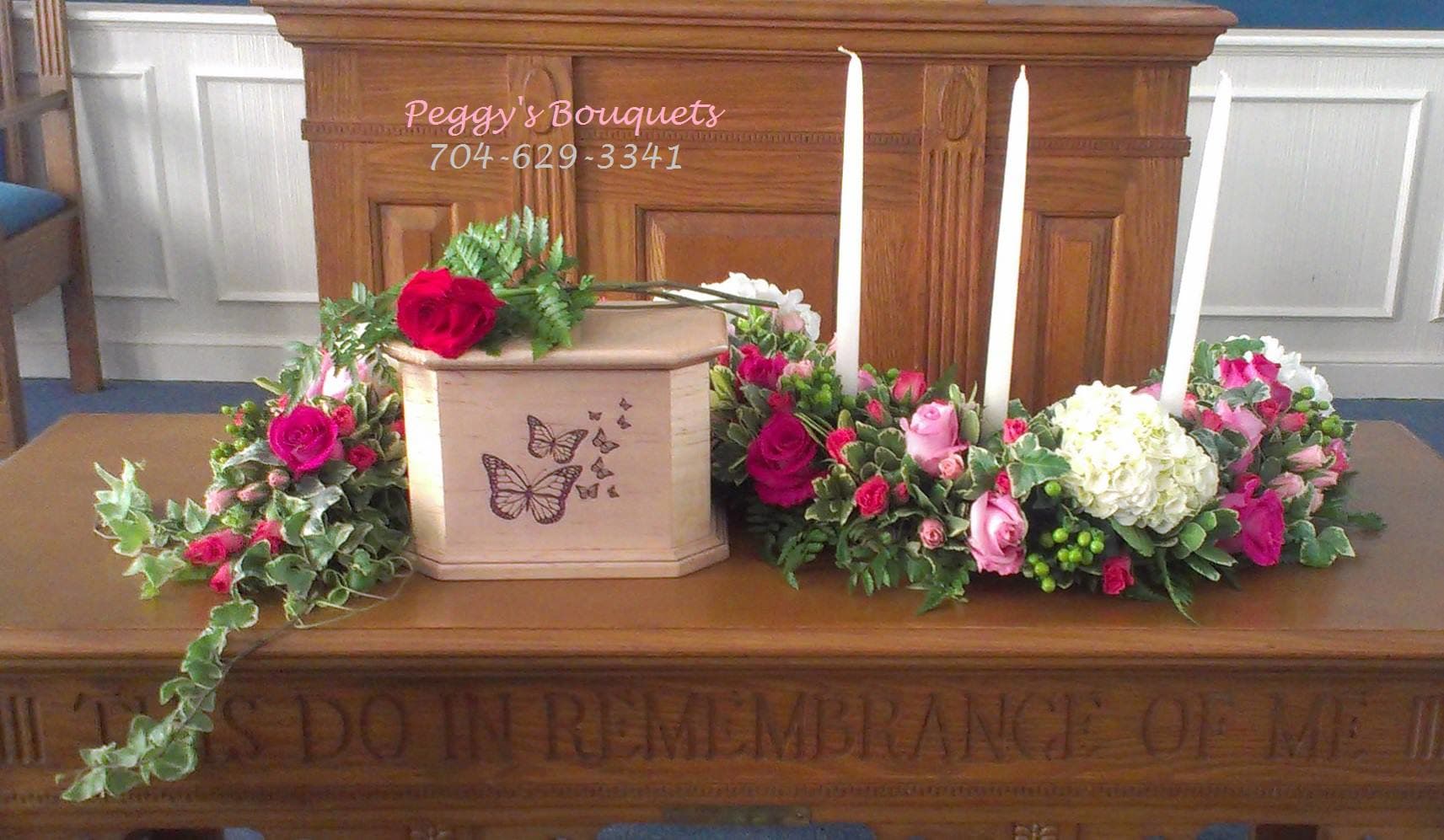 Casket spray with pink and white roses around a butterfly urn
