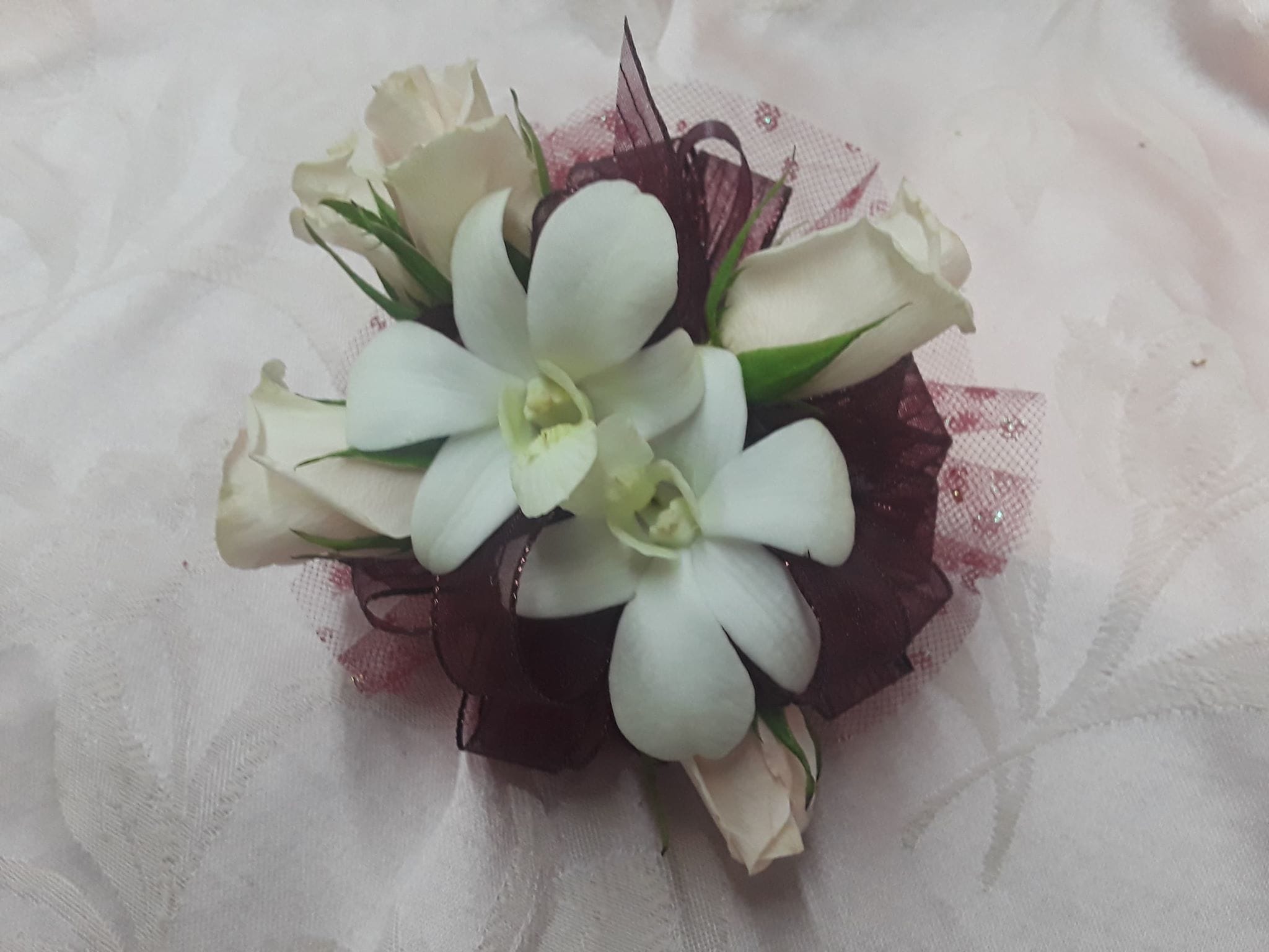 White orchid and rose corsage with burgundy ribbon accents