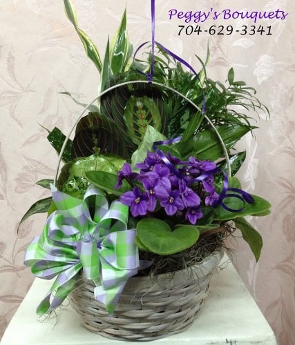 Purple flowers in a wicker basket with a green-and-lavender ribbon bow