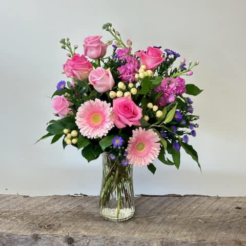 Pink Blossom - A tall vase with pink Gerber daisy's, pink and or white roses, hypericum berry, Pink or white stock and lemon leaf. colors are subject to change slightly.