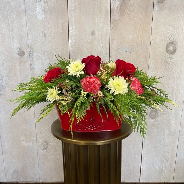Holiday centerpiece - This Holiday centerpiece has cedar with roses , white mums and red and white carnations in a rounded, rectangle Christmas Tin