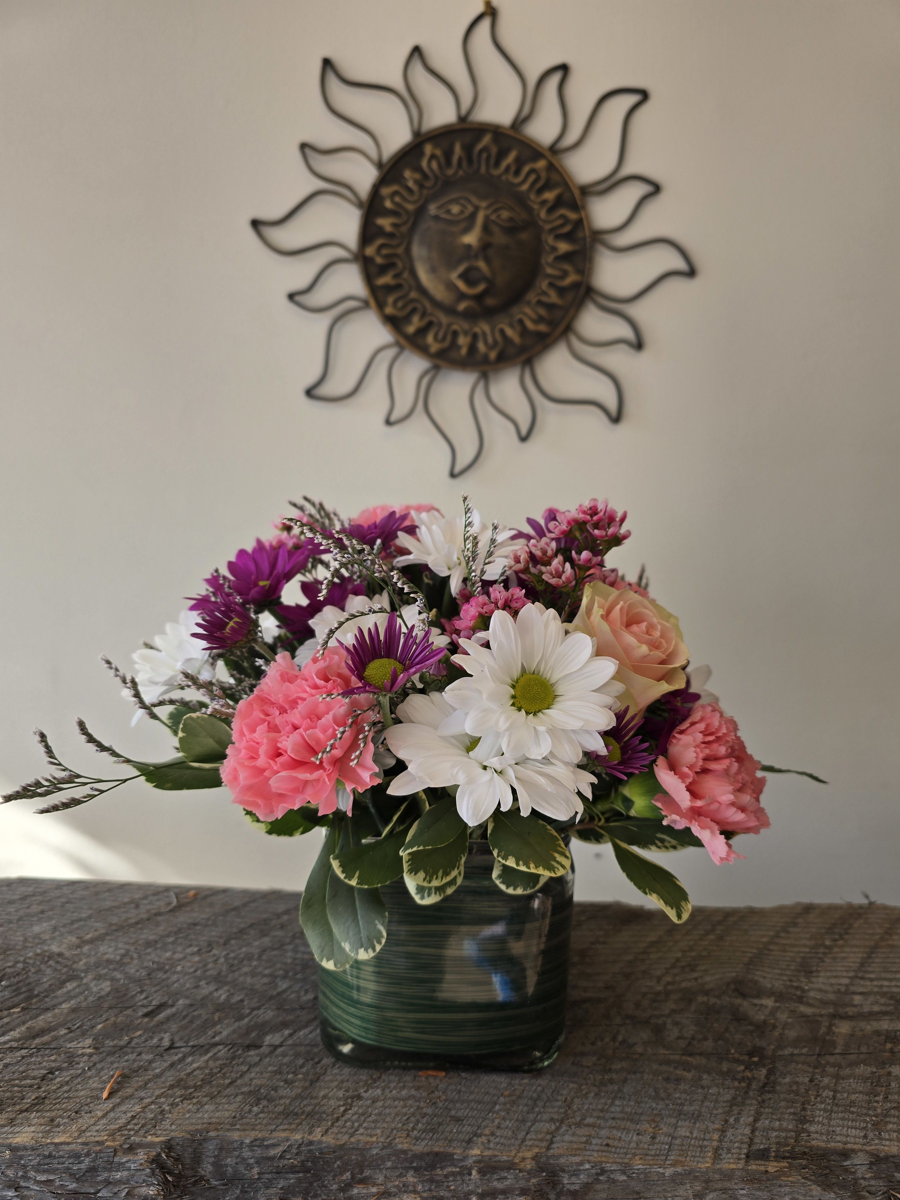Mixed bouquet in a square glass vase with pink, white, and purple flowers